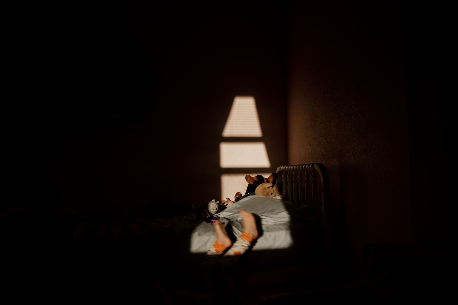 A silhouetted figure rests in a dark room with a glowing window casting soft light in the background norfolk, virginia in home session
