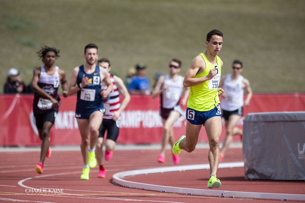Athletes compete in a track and field event at a stadium with red track surface.