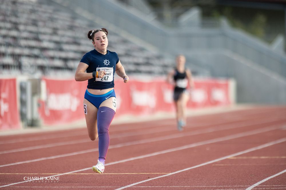 Athlete sprints down red track during competitive race.
