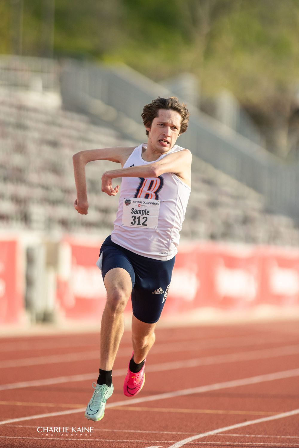 Runner sprints down red track at athletic competition.