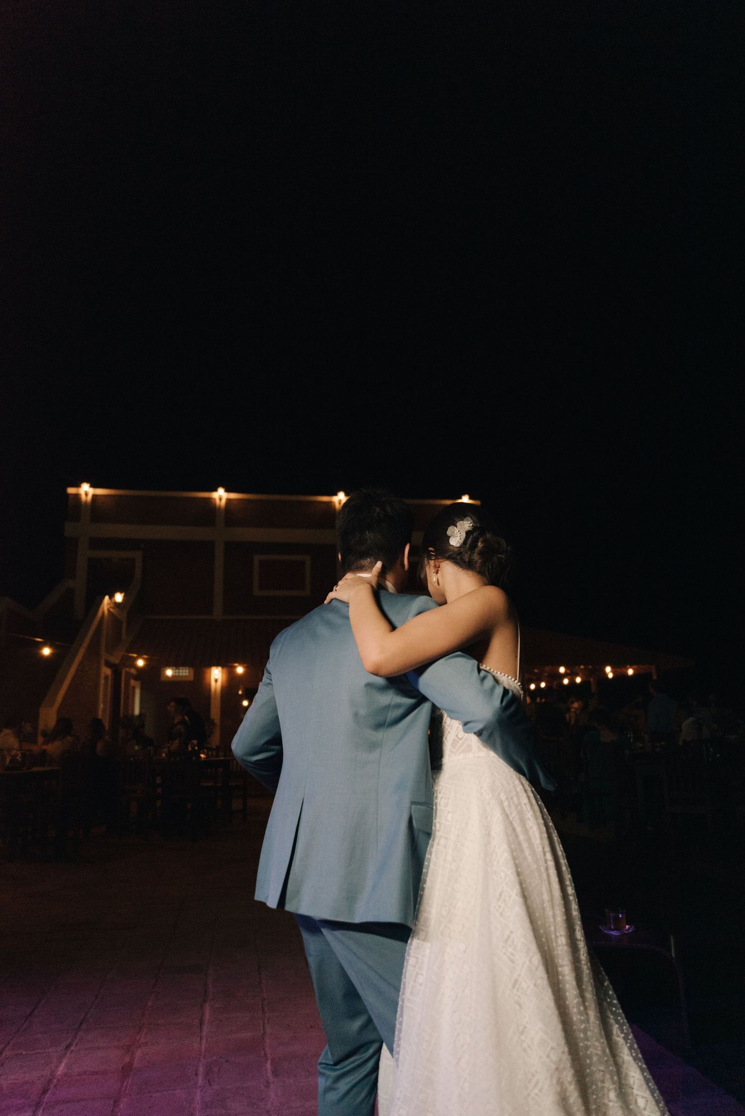 A couple shares a romantic slow dance at their evening wedding celebration.