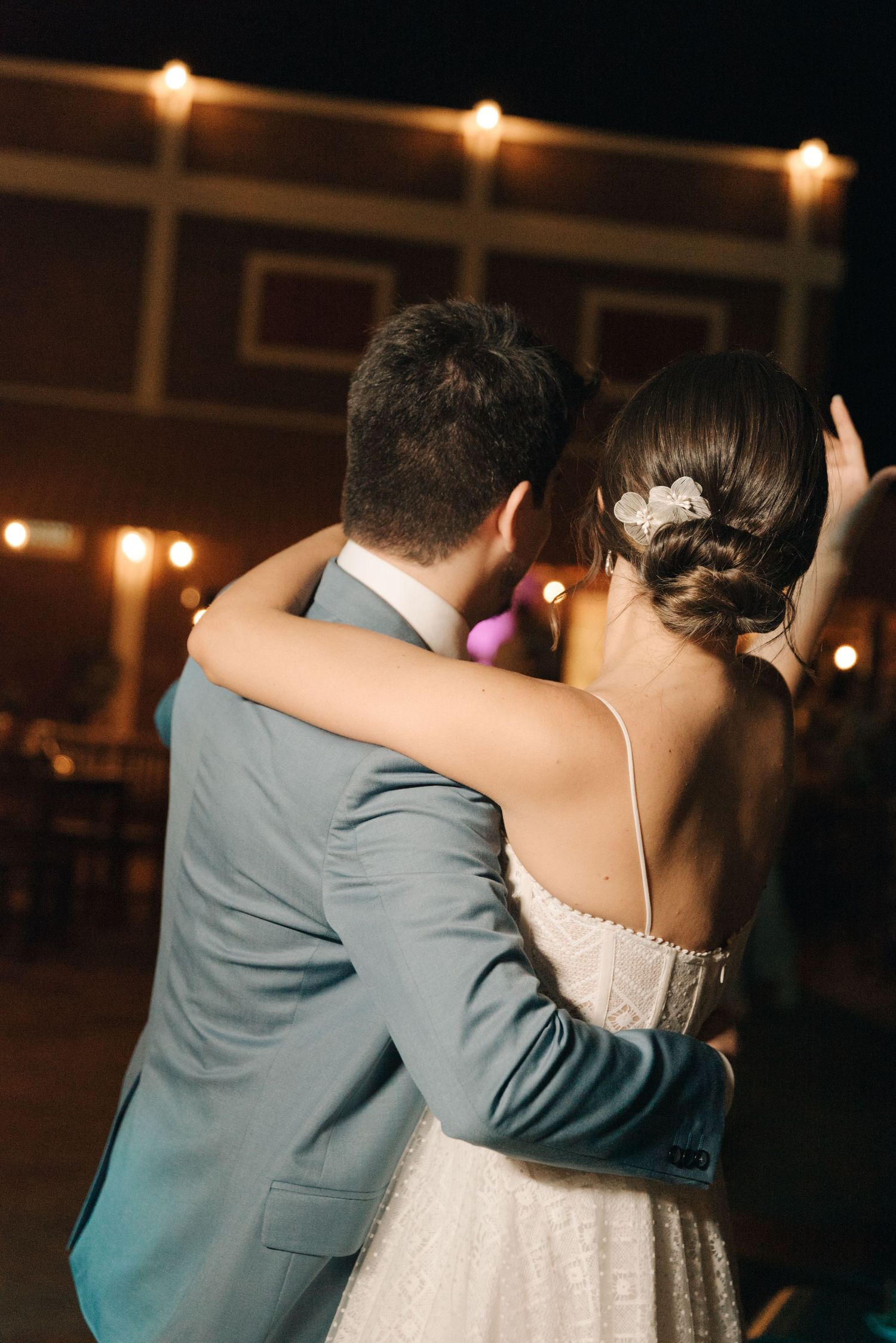 A couple dances closely together at their wedding reception with soft lighting overhead.