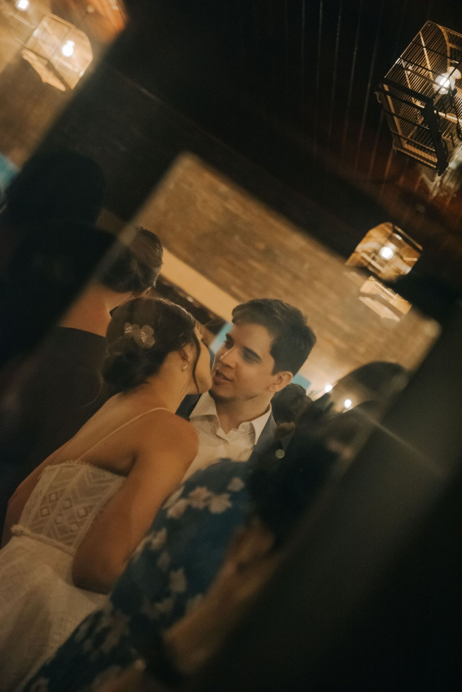 A couple shares an intimate moment during their wedding reception in a rustic indoor venue.