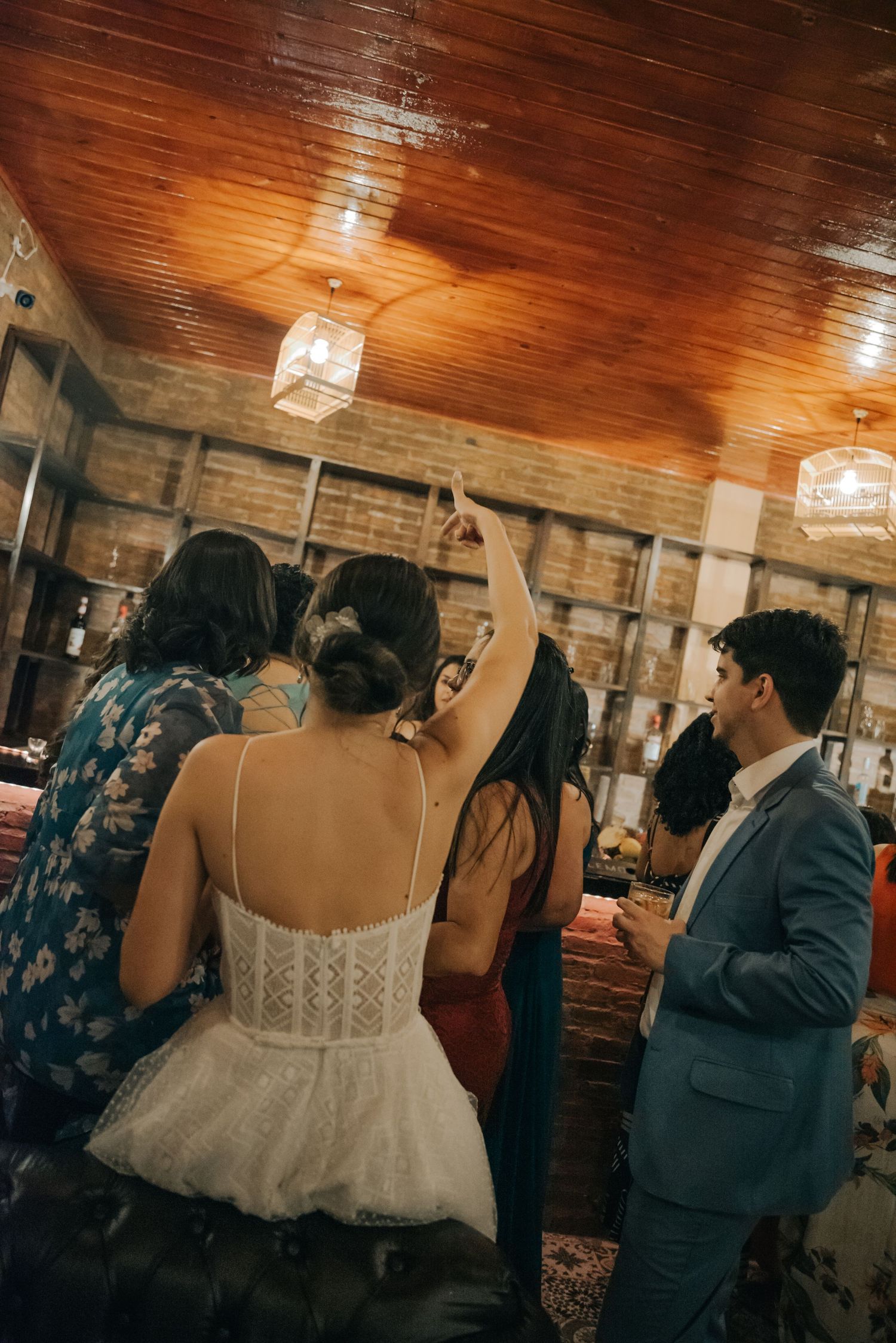 A rustic indoor wedding reception with wooden ceiling and hanging lanterns.