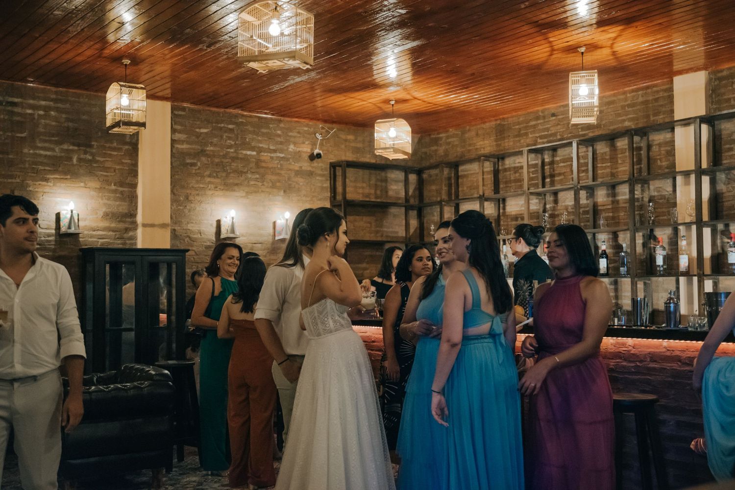 Wedding celebration in rustic venue with warm lighting and guests in colorful dresses.