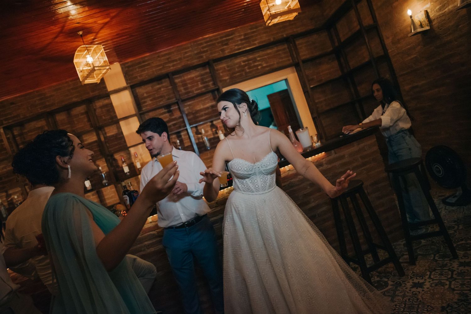 Lively dancing at rustic wedding reception with wooden walls and hanging lanterns.