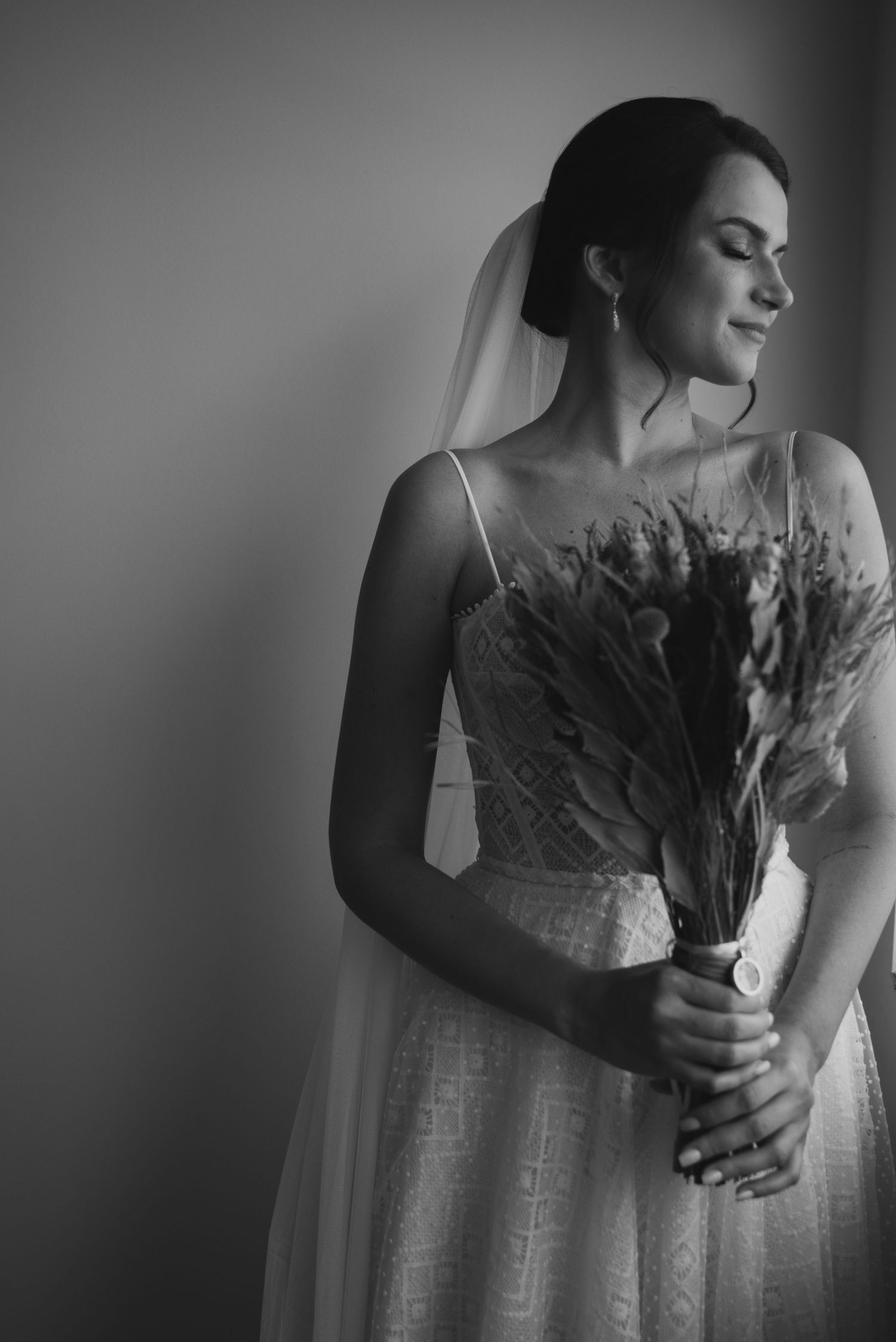 Black and white portrait of bride holding dried flower bouquet.