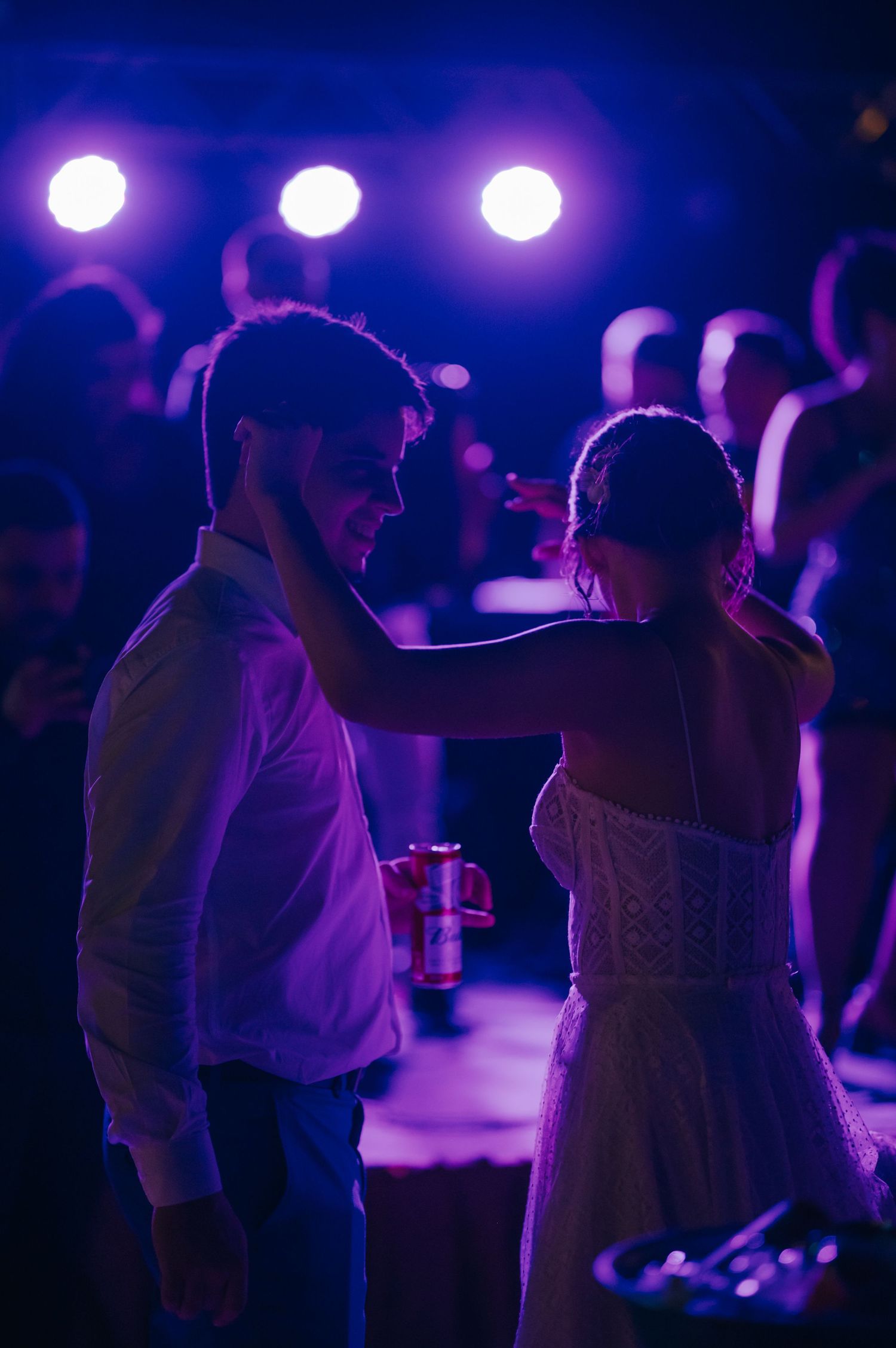 Purple-lit dance floor moment between couple at wedding reception.