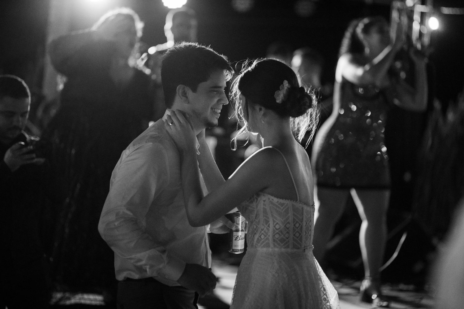 A black and white photo captures a couple dancing closely at an evening reception.