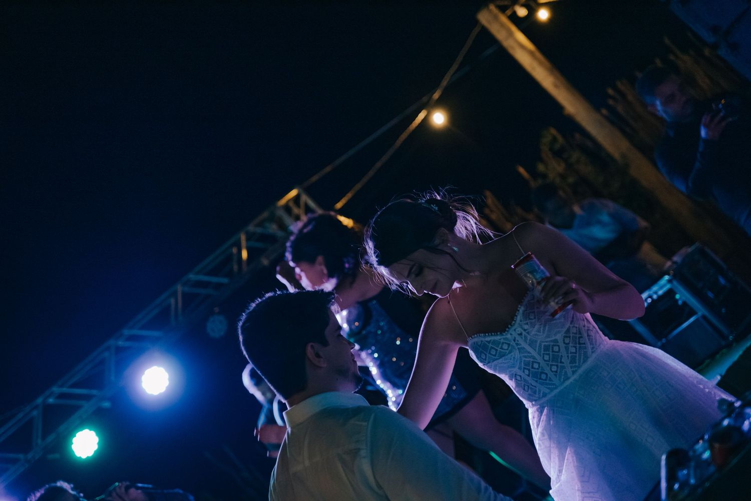 Couples dancing under dramatic blue lighting at a nighttime outdoor party venue.