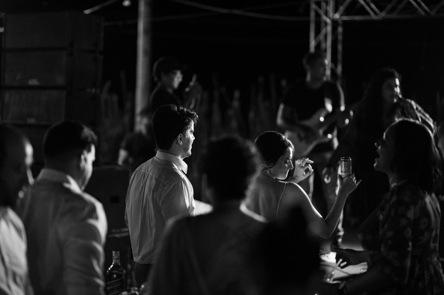 A monochrome image captures the silhouettes of party guests mingling in the evening.