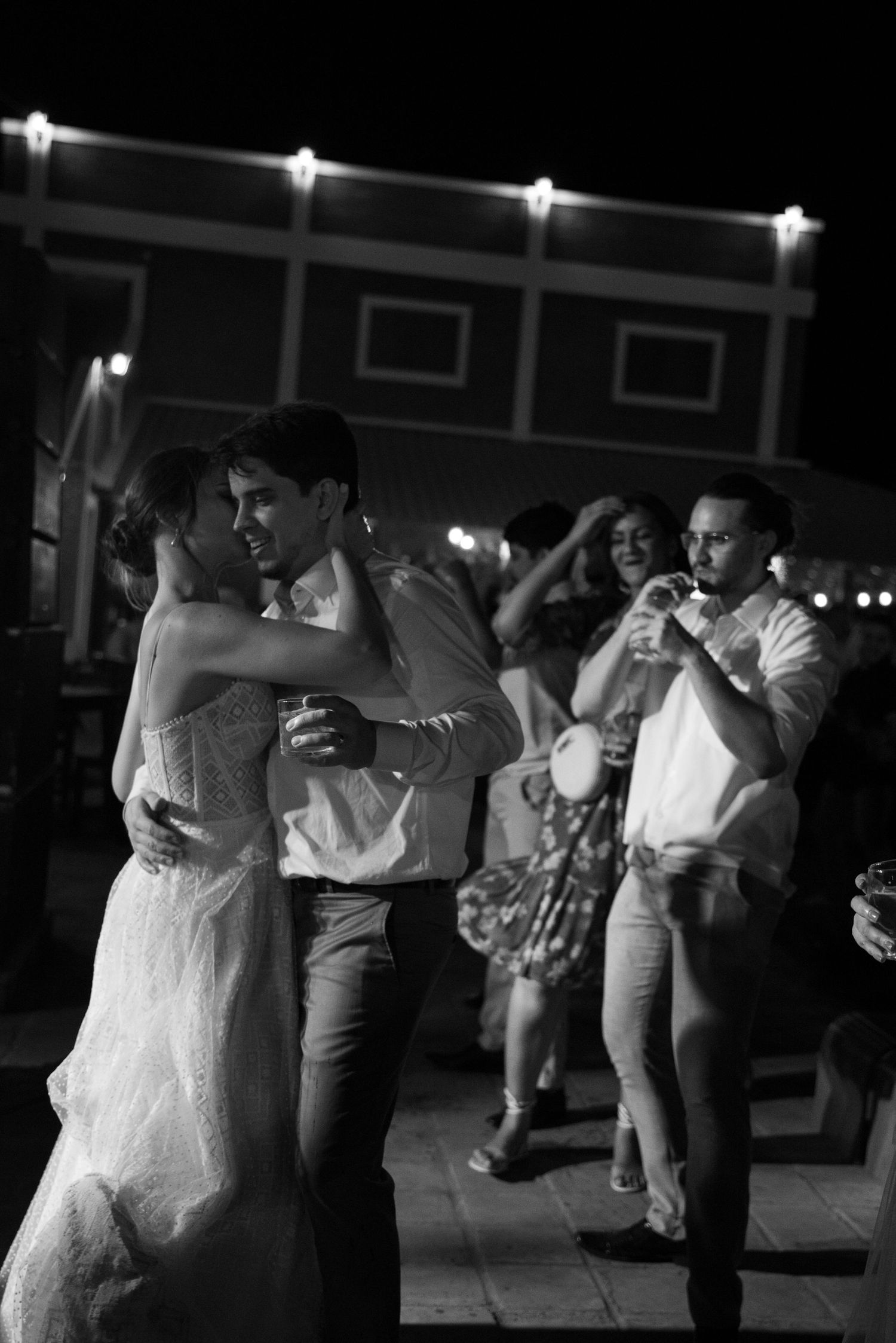 A black and white photo shows couples slow dancing at an outdoor evening celebration.