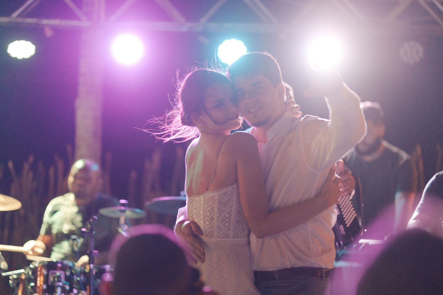 A couple shares a romantic slow dance under purple and blue stage lighting.