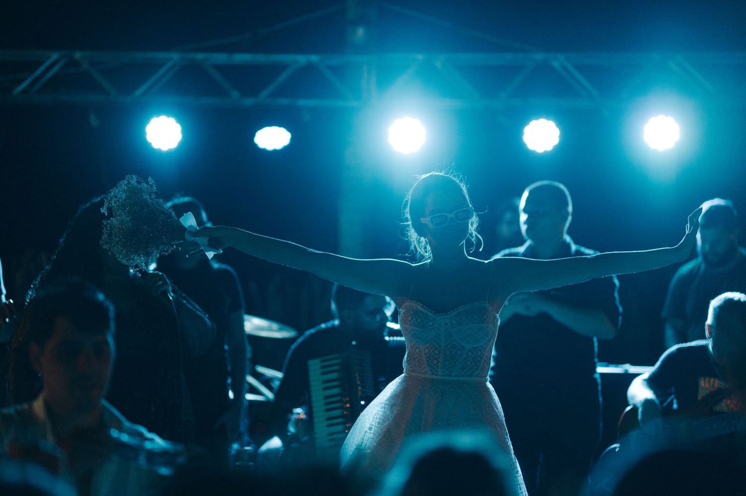 A wedding reception dance floor illuminated by blue stage lights as dancers celebrate in silhouette.