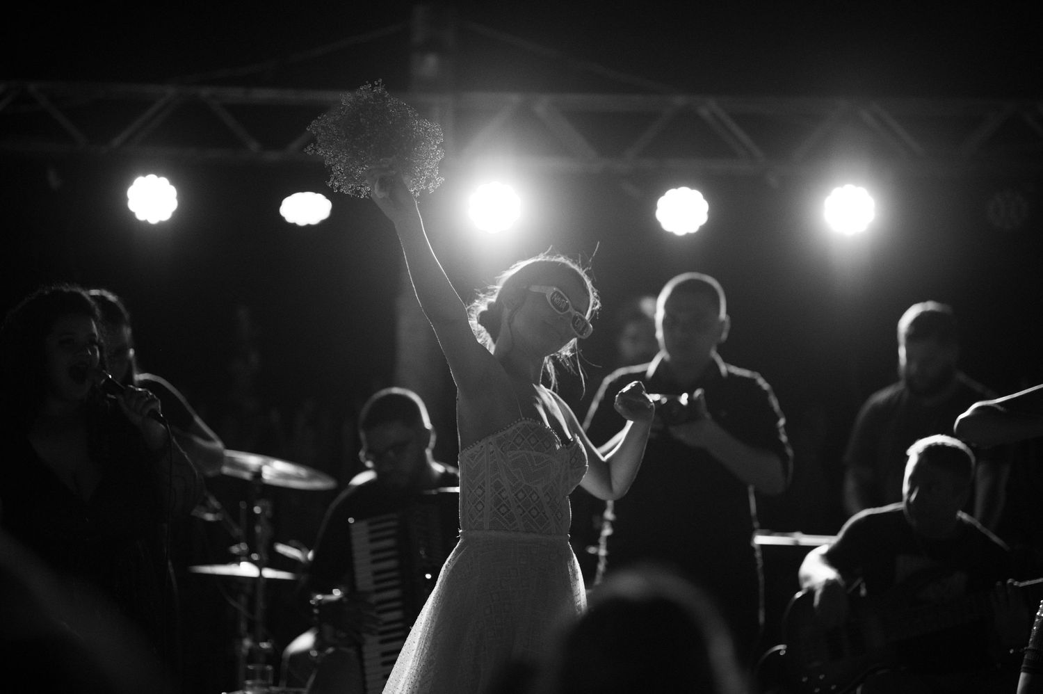 A black and white photo of dancers silhouetted against bright stage lighting at a celebration.