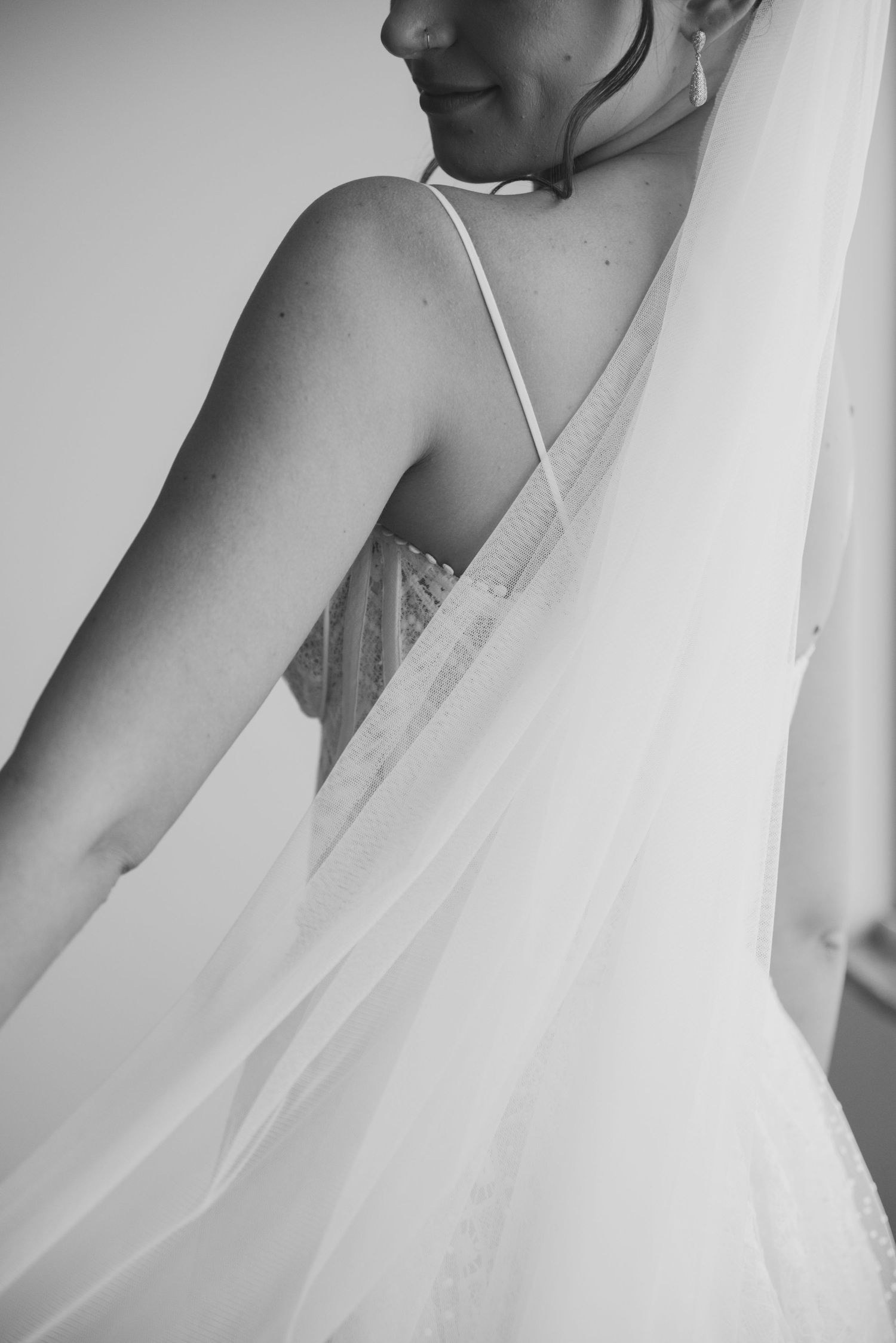 Artistic black and white close-up of bridal dress strap and veil.
