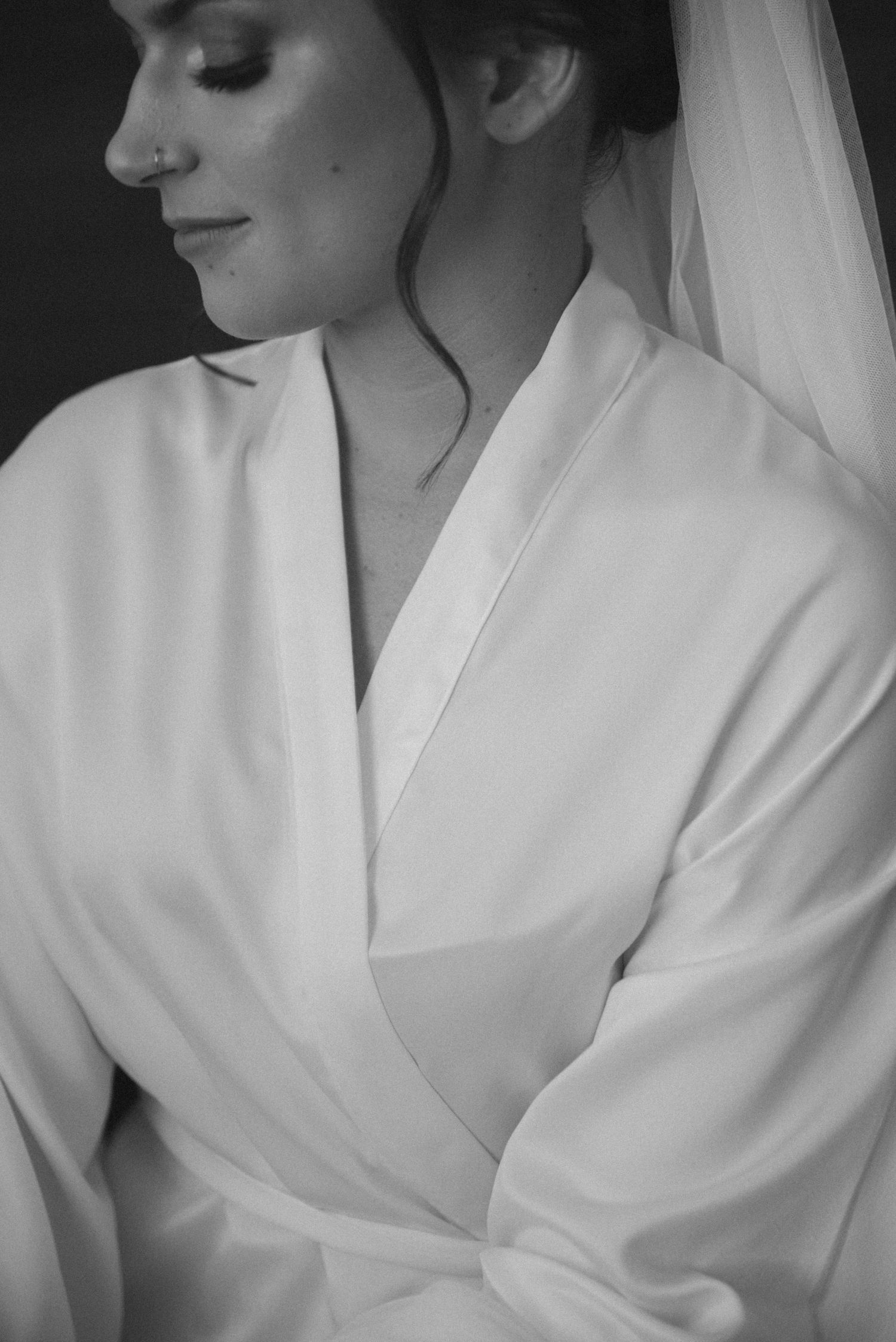 A black and white portrait showing someone in a white silk robe with elegant hair styling.