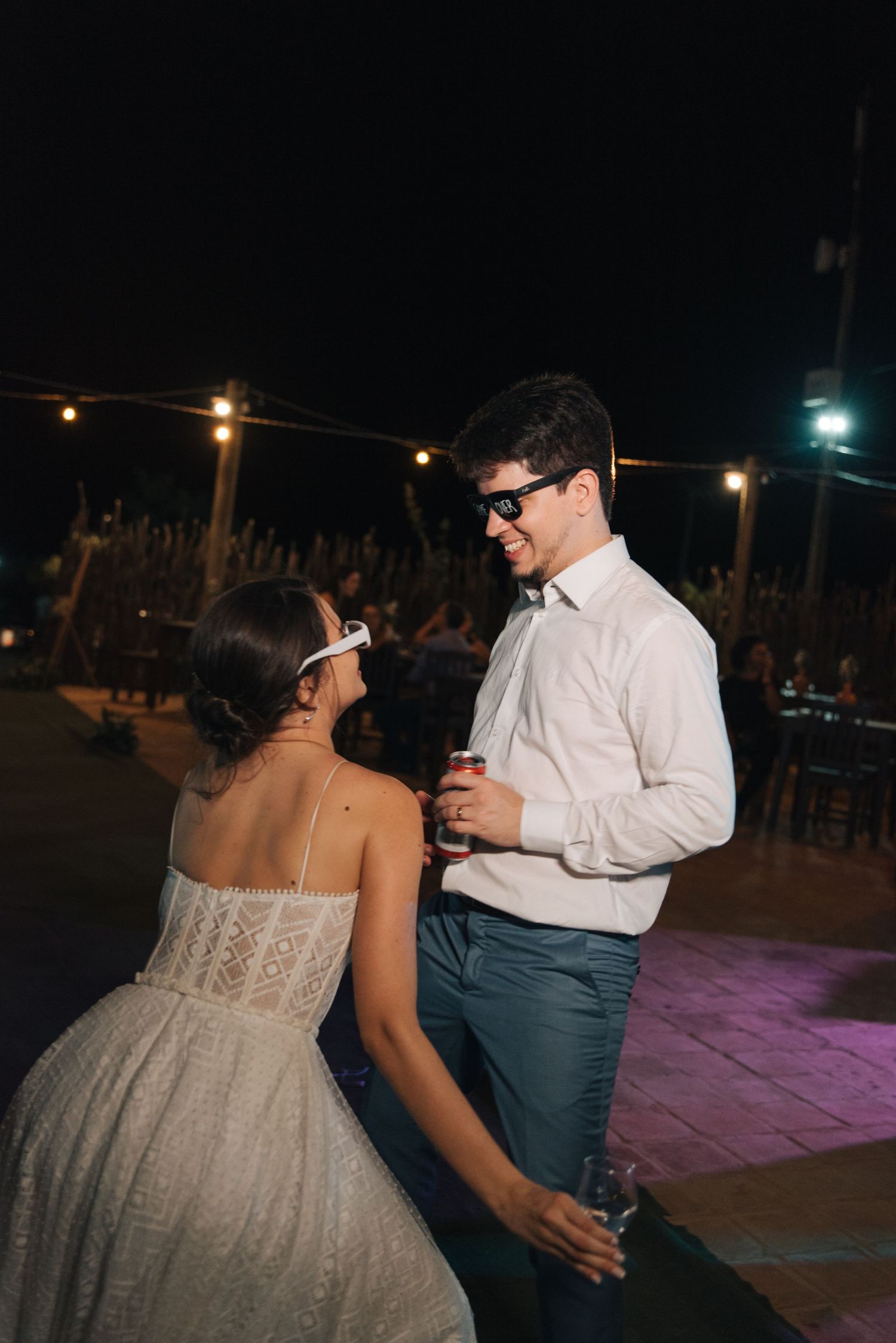 Couple dancing together at night under string lights at outdoor venue.
