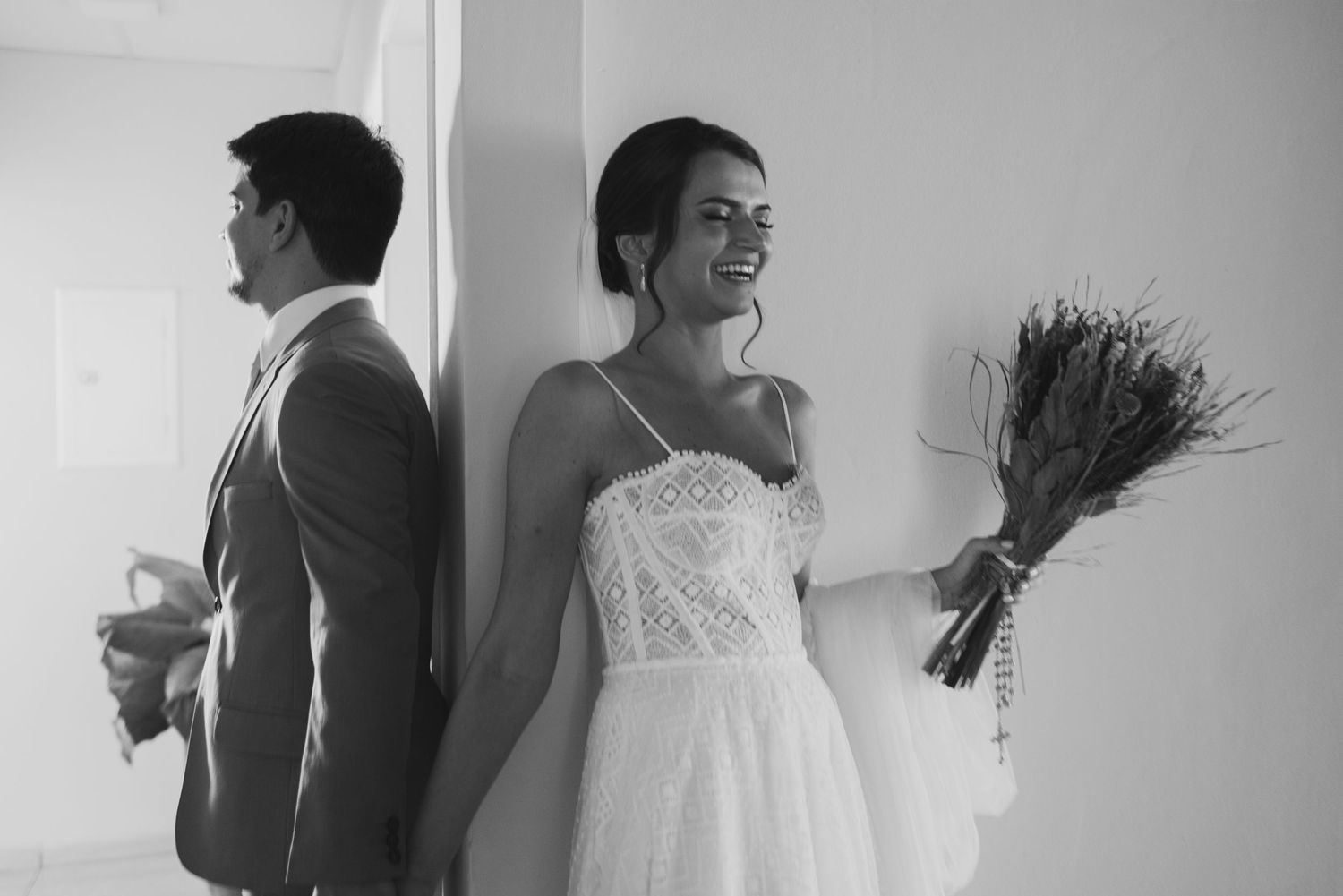 Black and white photo of bride and groom sharing a first look moment with bouquet.