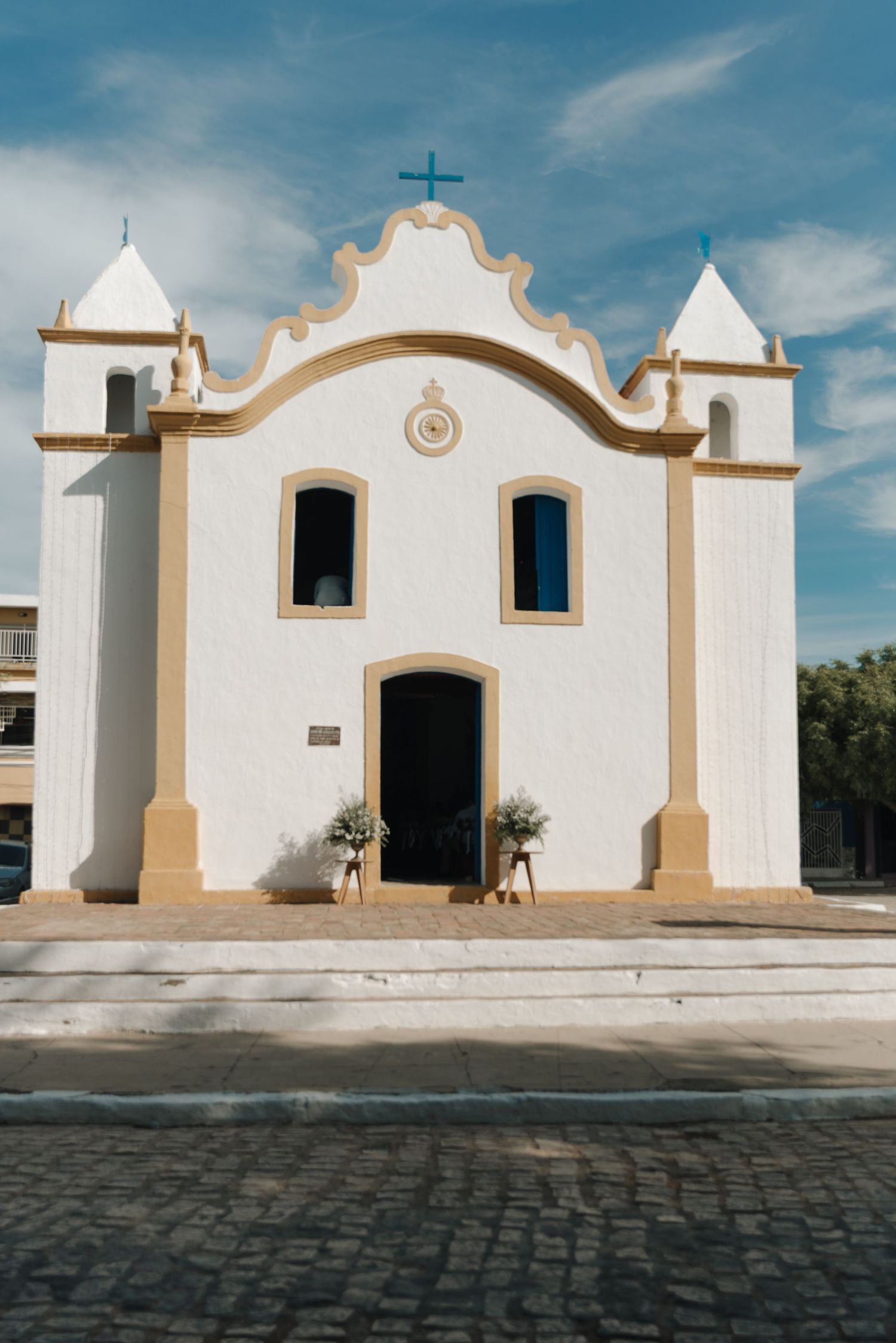 White colonial church with ornate facade and twin towers against blue sky.