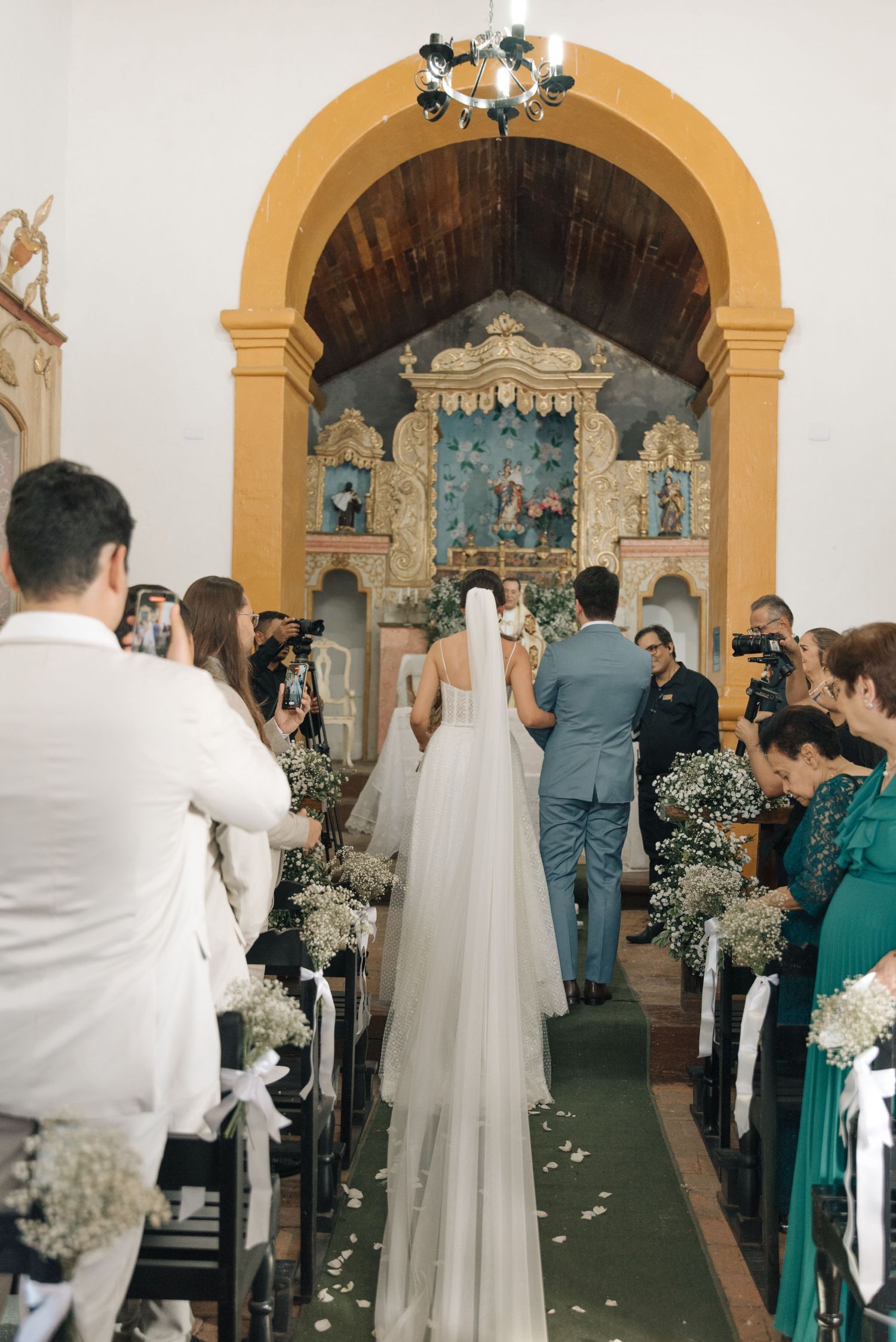 Wedding ceremony inside a historic church with floral decorations and guests lining the aisle.