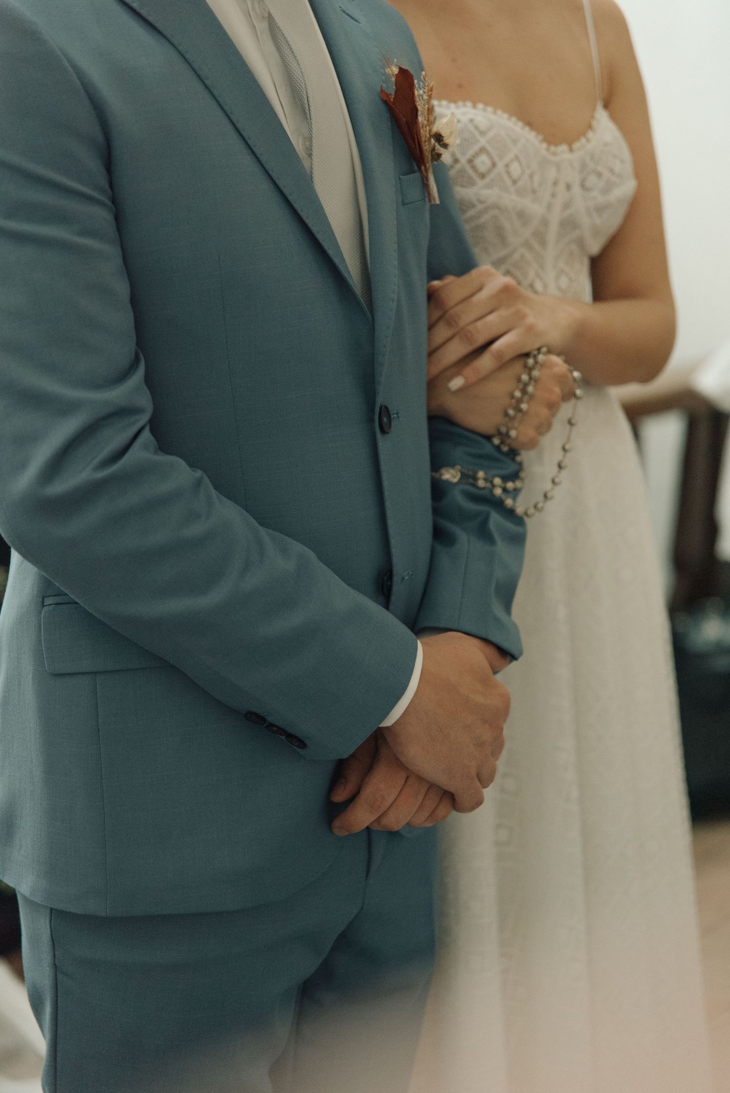 Close-up detail of a couple in formal wedding attire showing a blue suit and white lace gown.