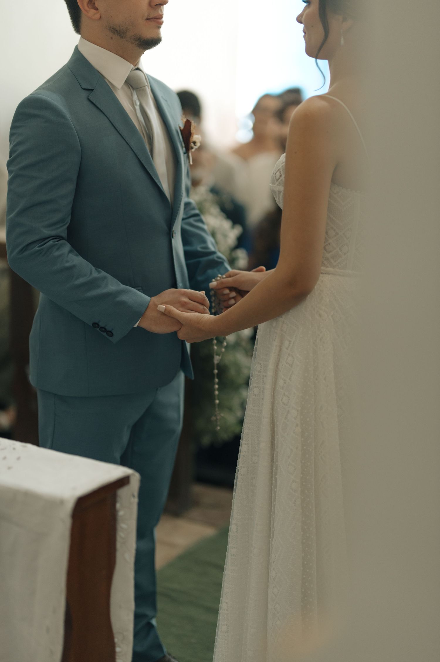 A couple holds hands during an intimate wedding ceremony in a church.