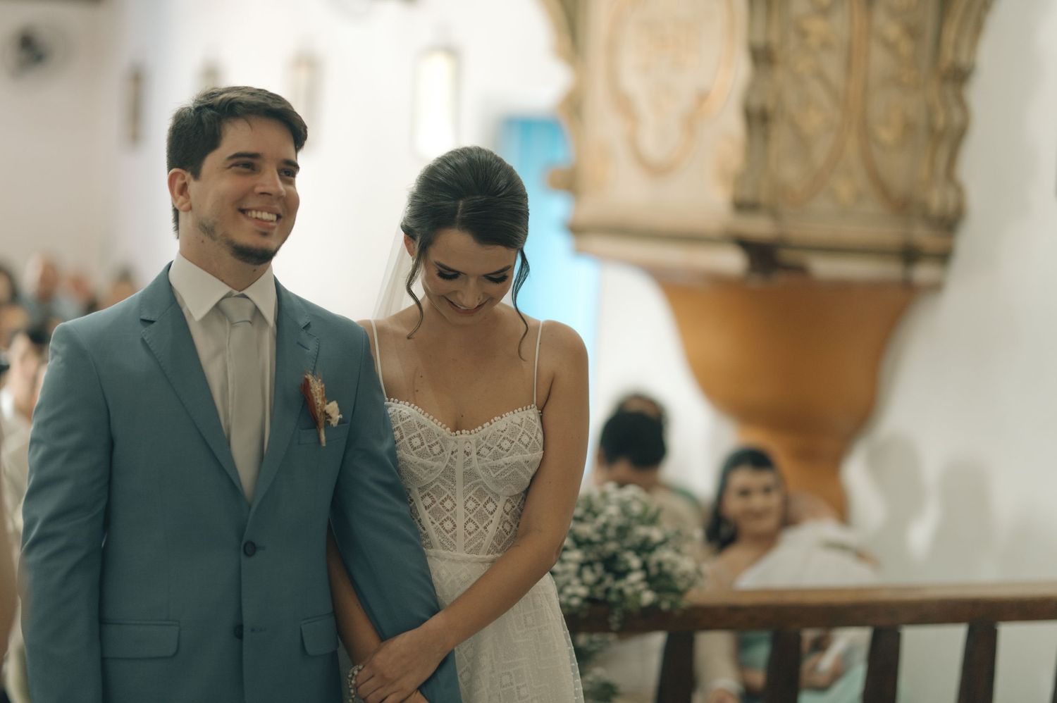 A couple shares a joyful moment during their wedding ceremony in a traditional church setting.
