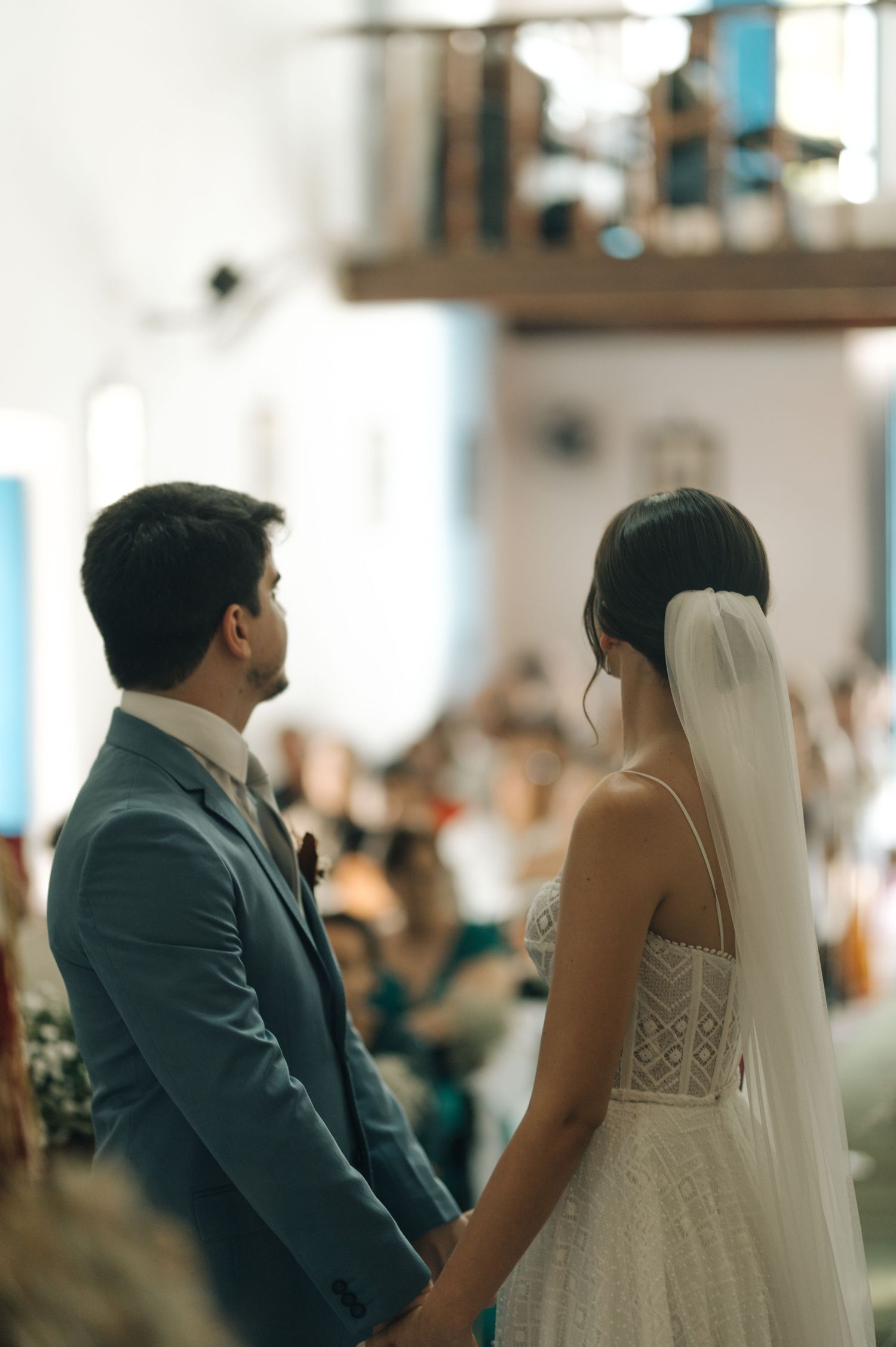 A couple stands at the altar during their wedding ceremony in a sunlit church.