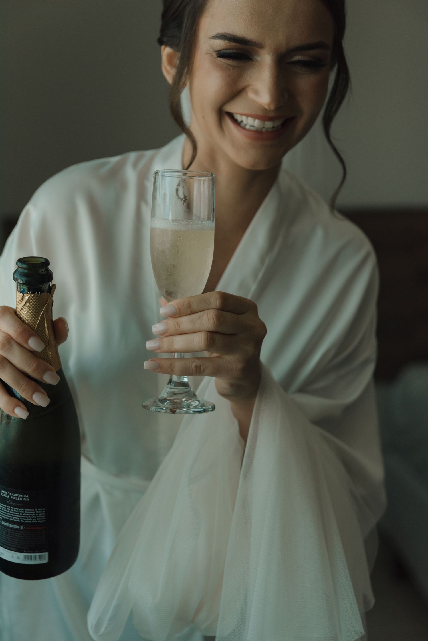 A candid moment of joy while pouring celebratory champagne in bridal robe.