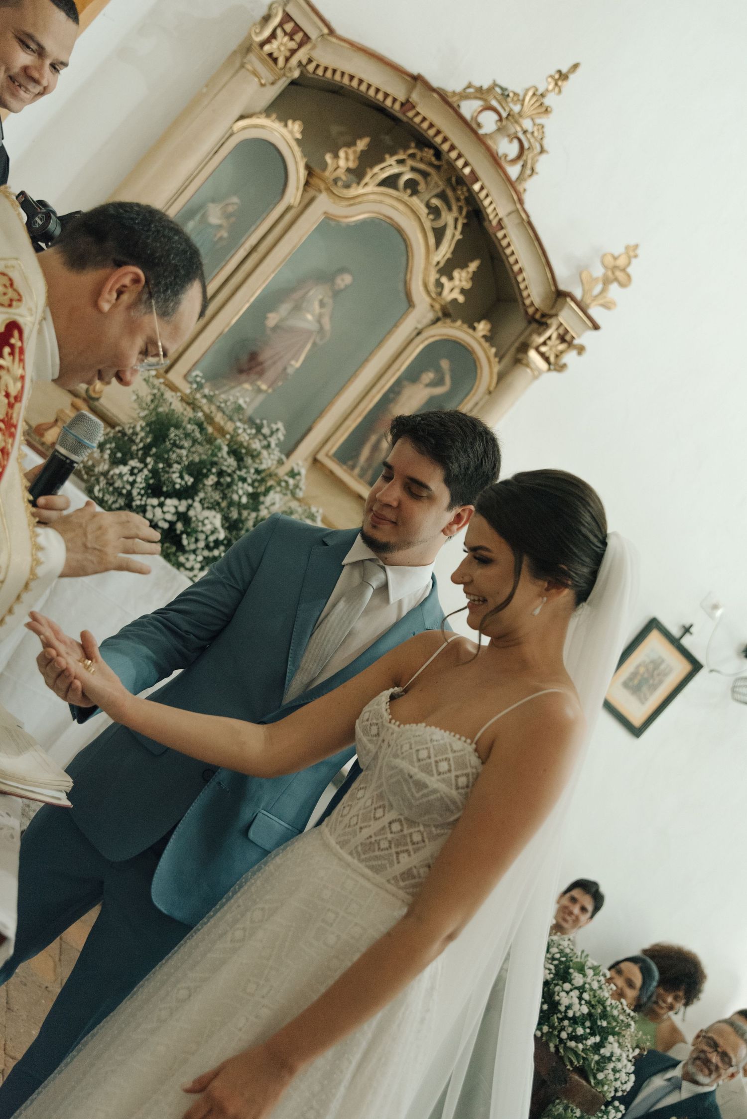 A wedding ceremony in progress with guests and an ornate altar in the background.