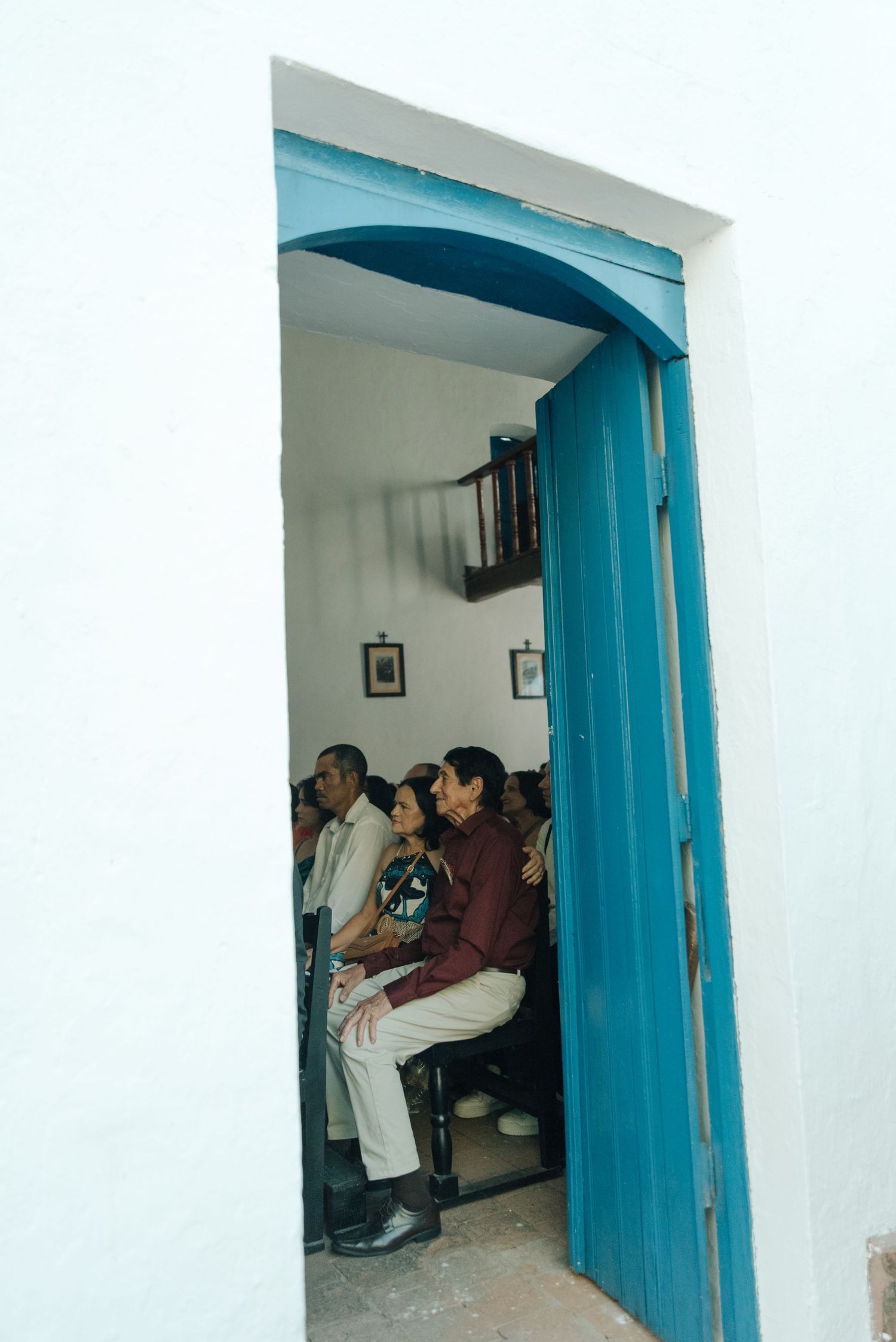 Wedding guests seated in a room with a bright blue doorway.
