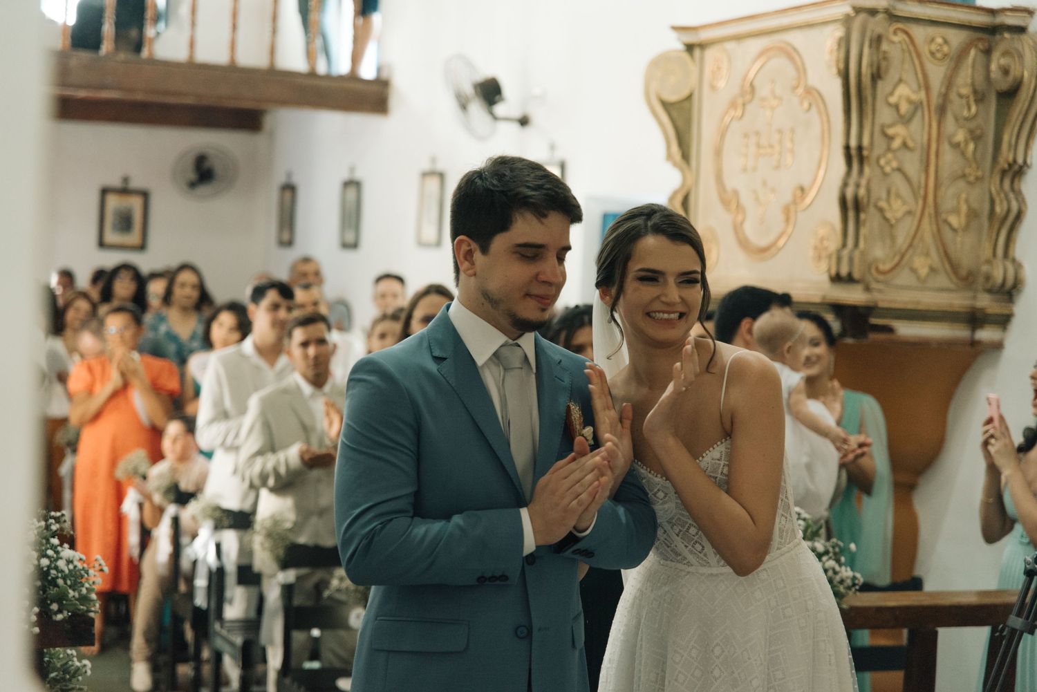 A couple shares a joyous moment during their wedding ceremony inside a traditional church.