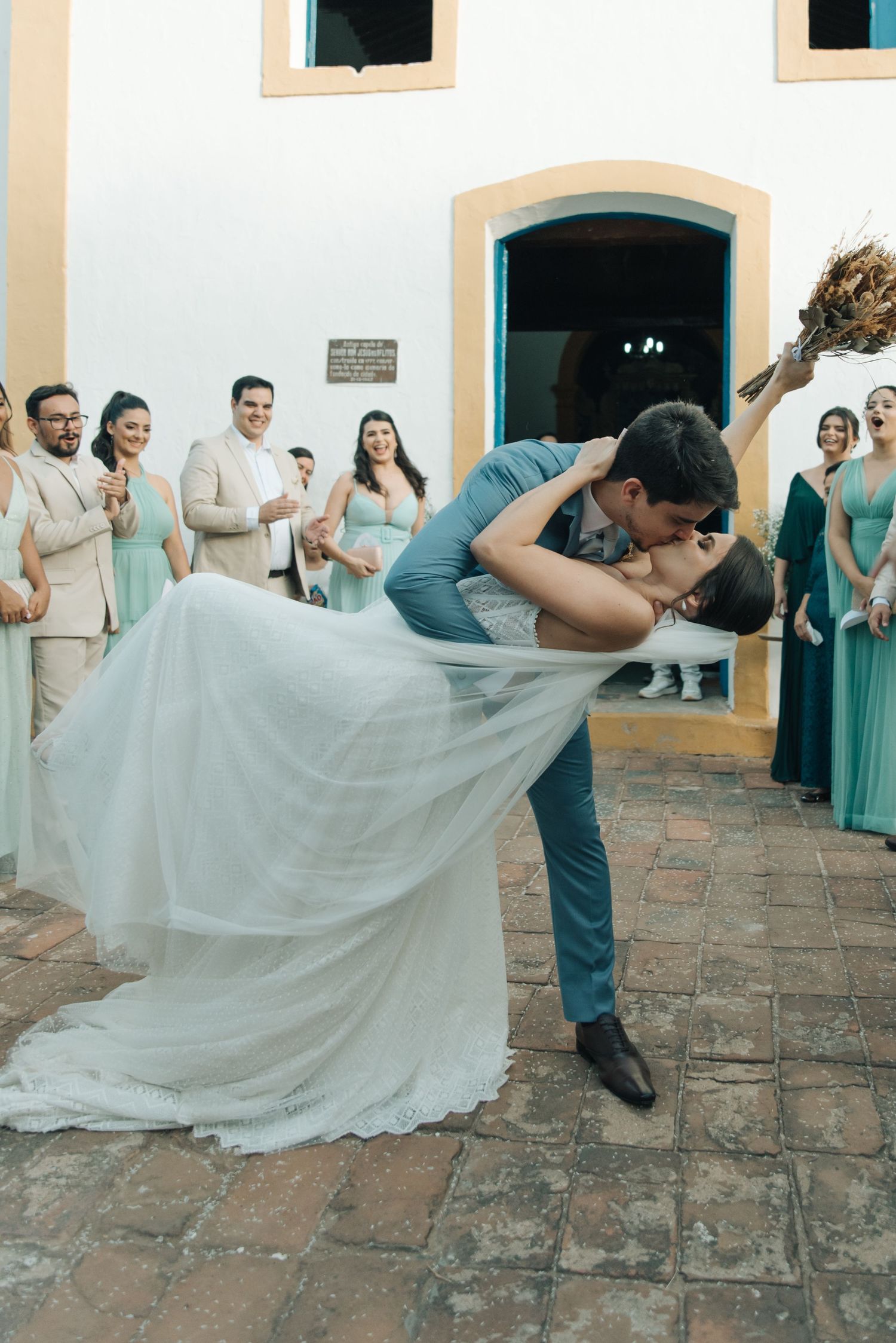 Dramatic wedding dip kiss with bridesmaids in mint green dresses watching in background.
