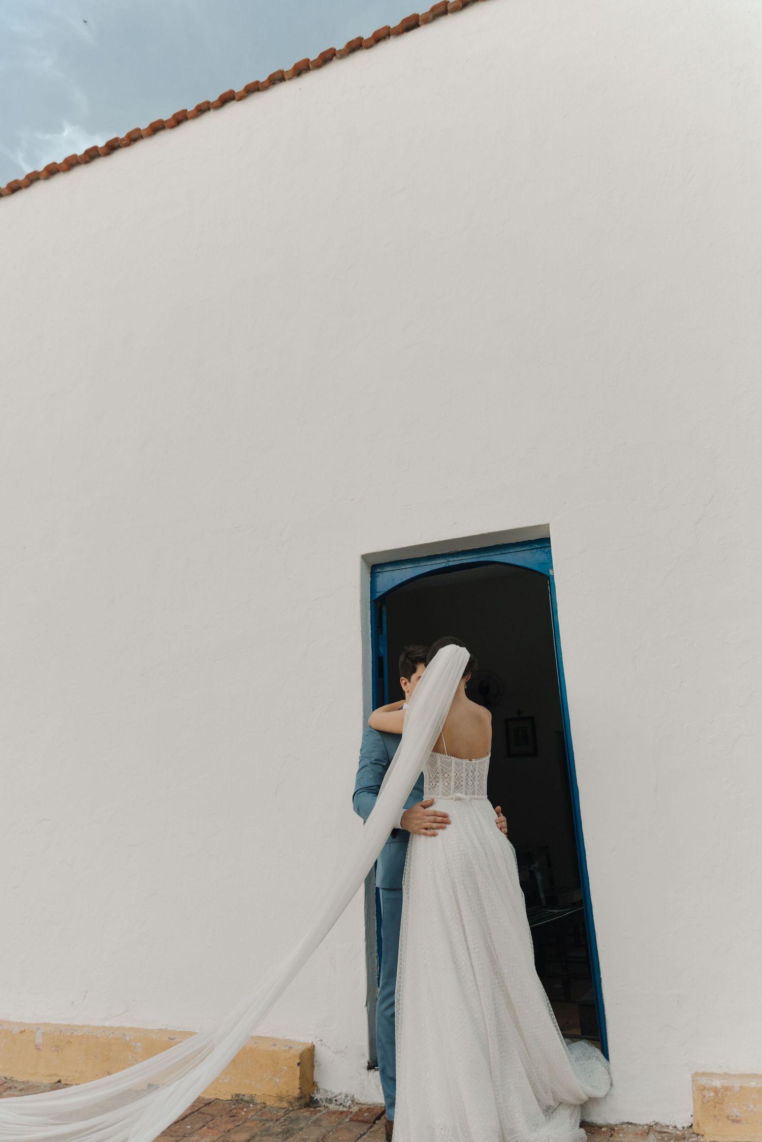 A wedding couple sharing an intimate moment in a white church doorway.