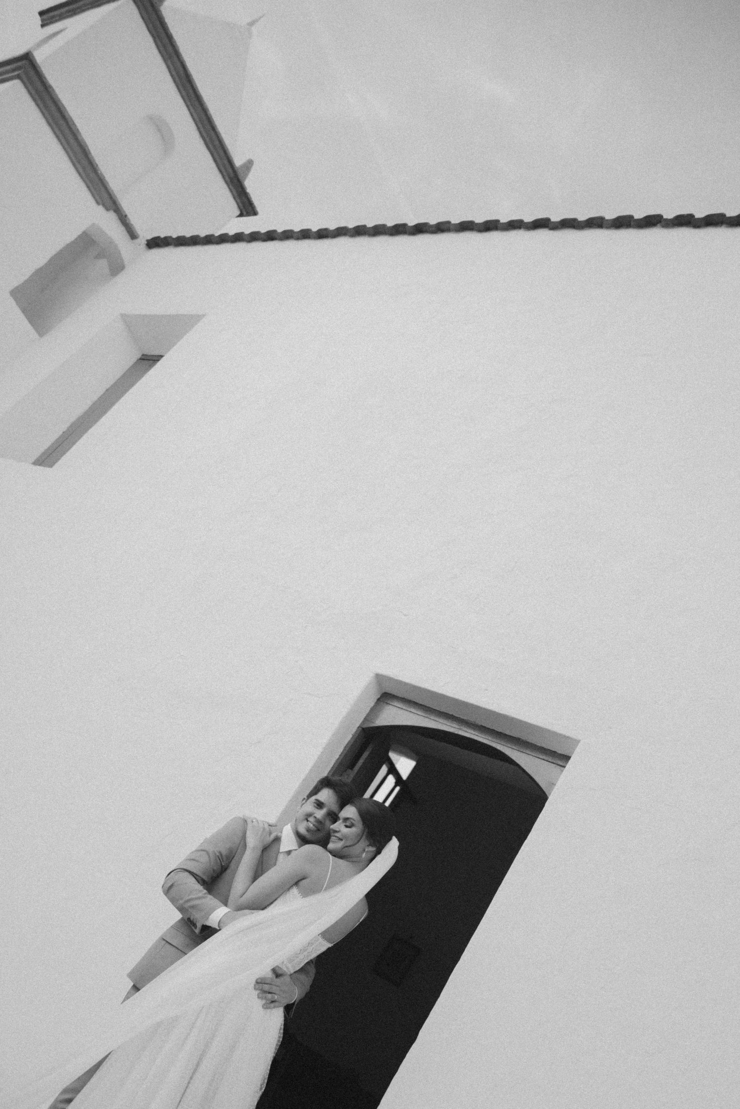 A black and white artistic wedding portrait in a church doorway.
