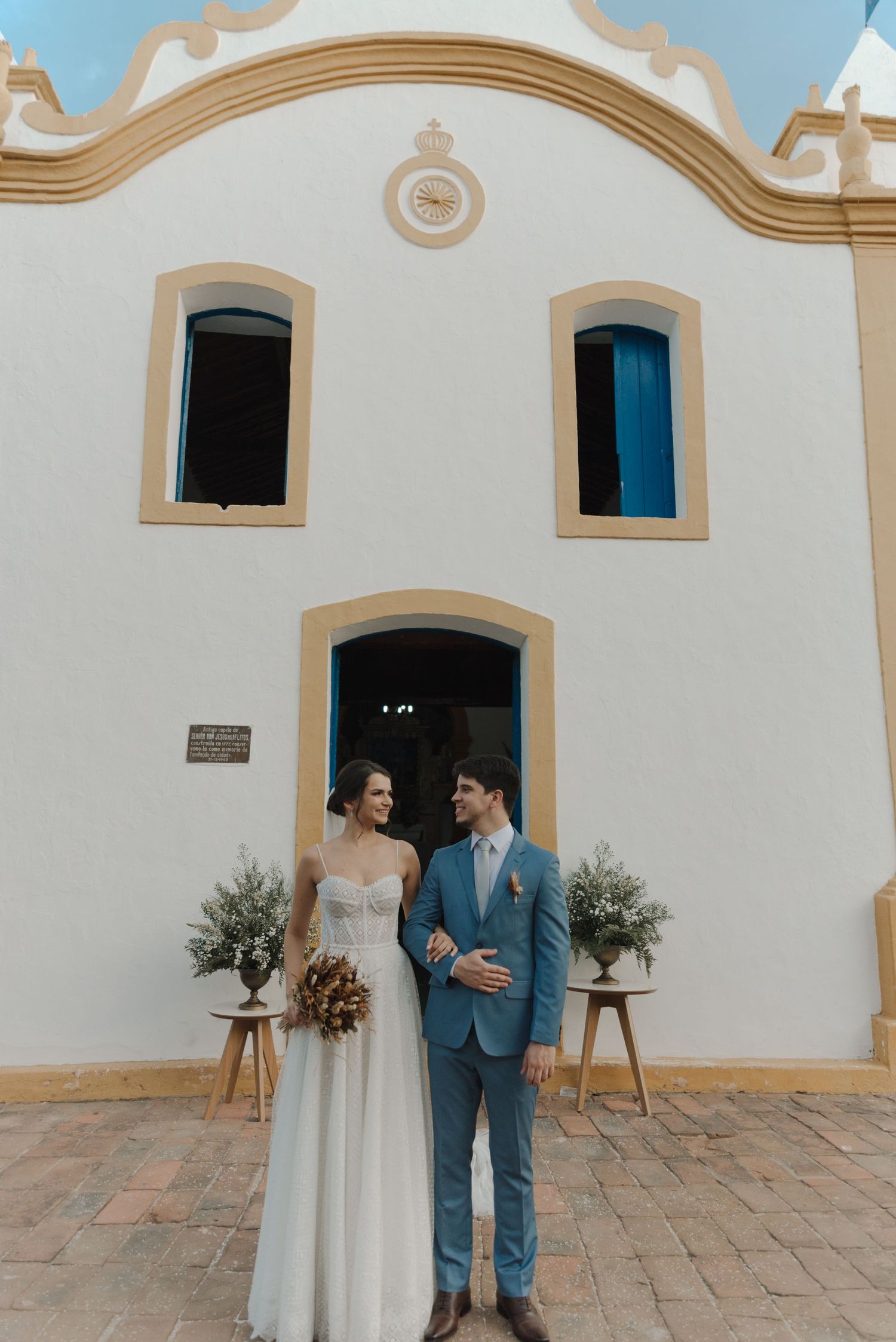 A classic wedding portrait in front of a white Portuguese-style church facade.