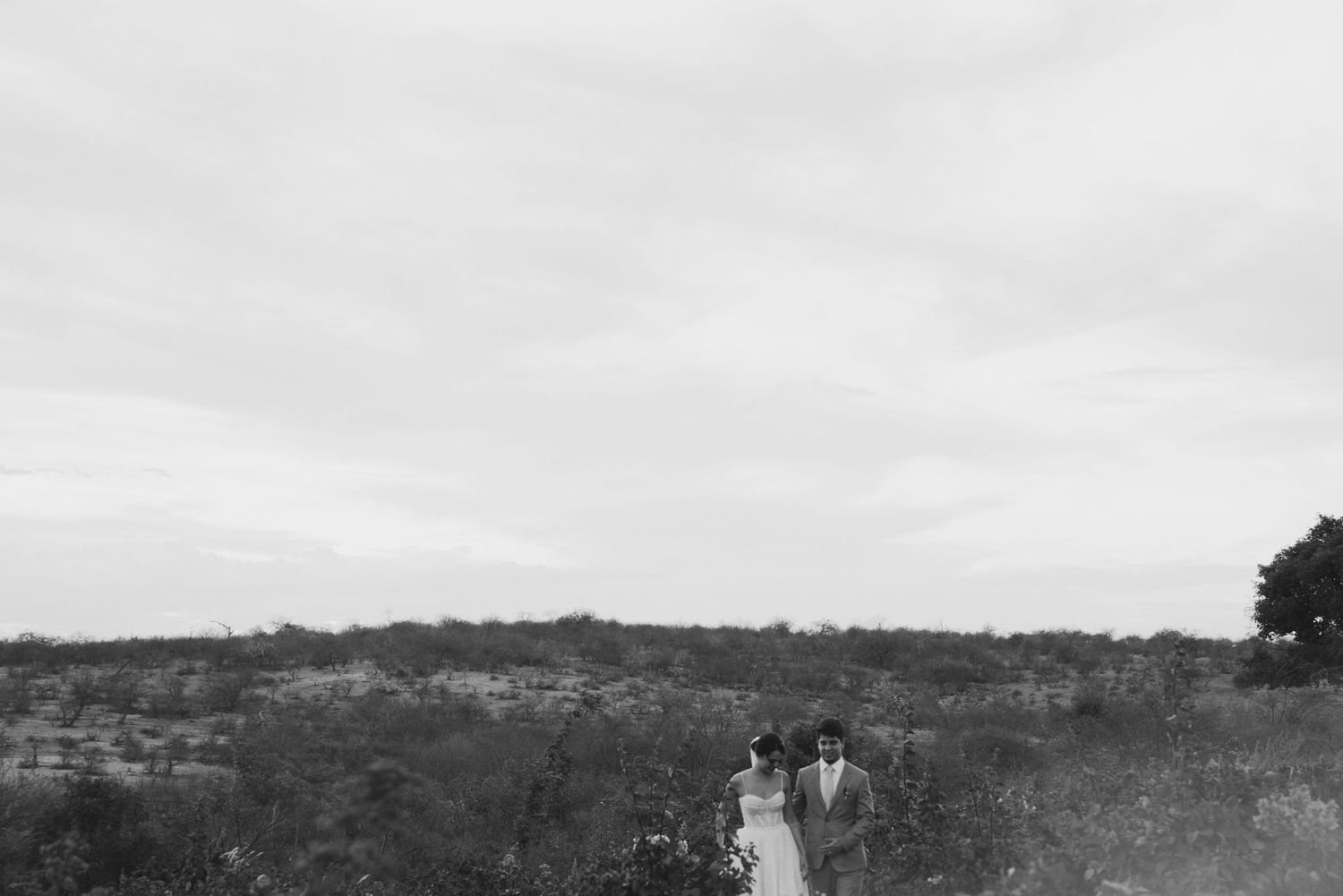 Black and white landscape wedding photo of couple standing together in an open field.