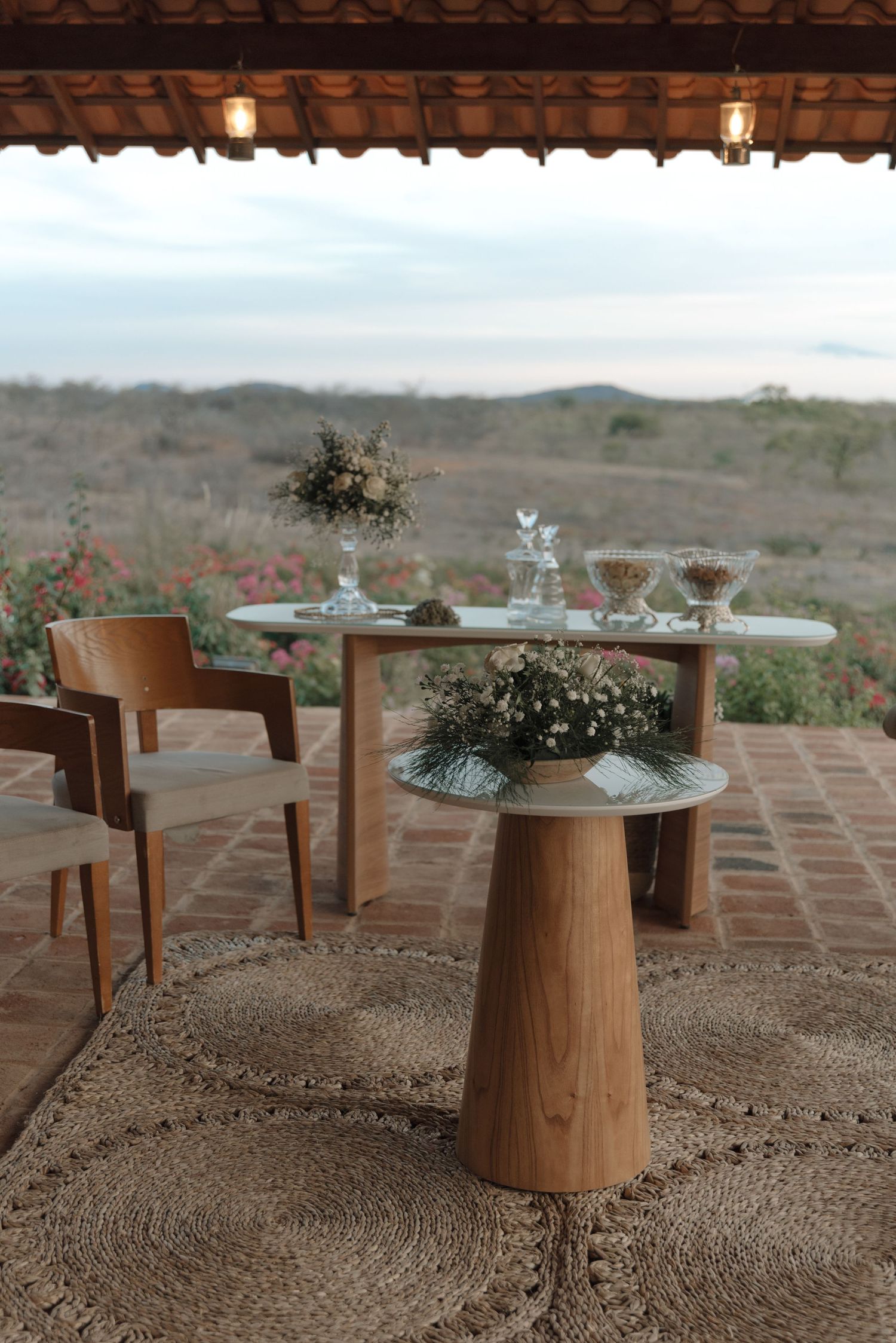 Modern wedding reception table setup with wooden furniture and glass decor overlooking scenic landscape.