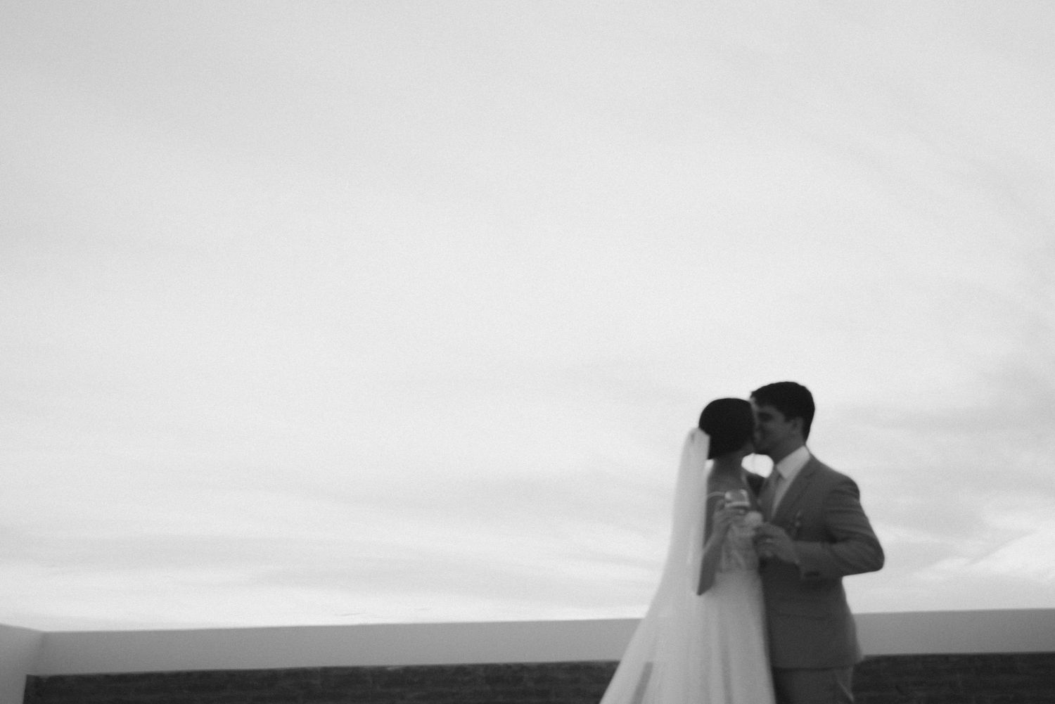 Black and white wedding portrait silhouette against cloudy horizon.