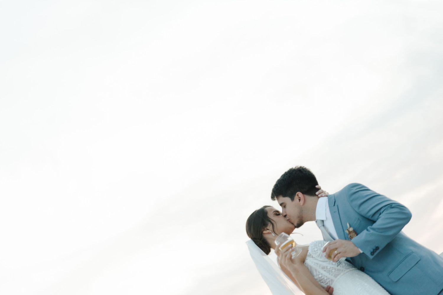 Romantic wedding couple sharing an intimate moment against bright white background.