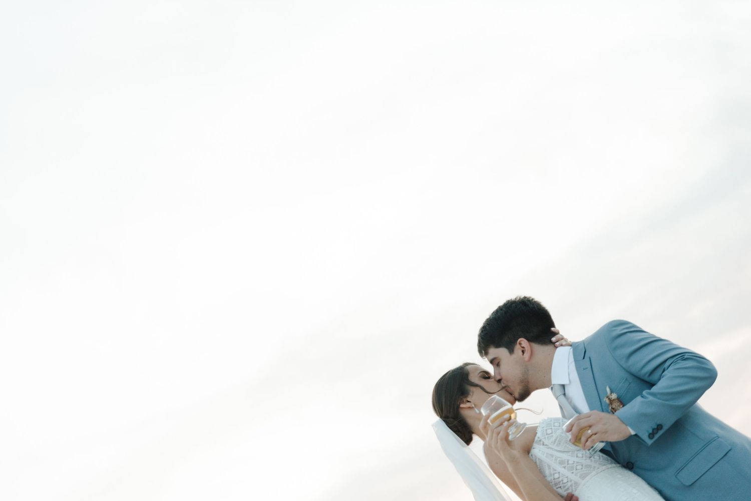 Wedding couple in tender embrace against minimalist white background.