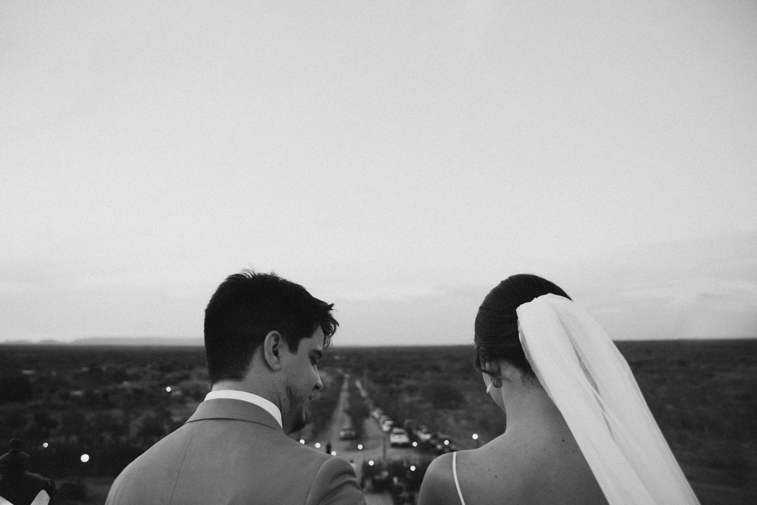 Black and white portrait of newlyweds gazing at distant scenery.