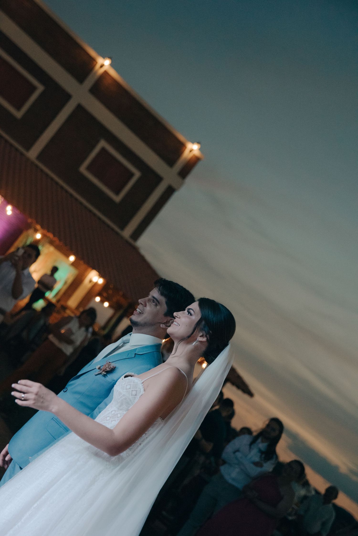Sunset wedding moment with couple gazing at sky under venue lighting.
