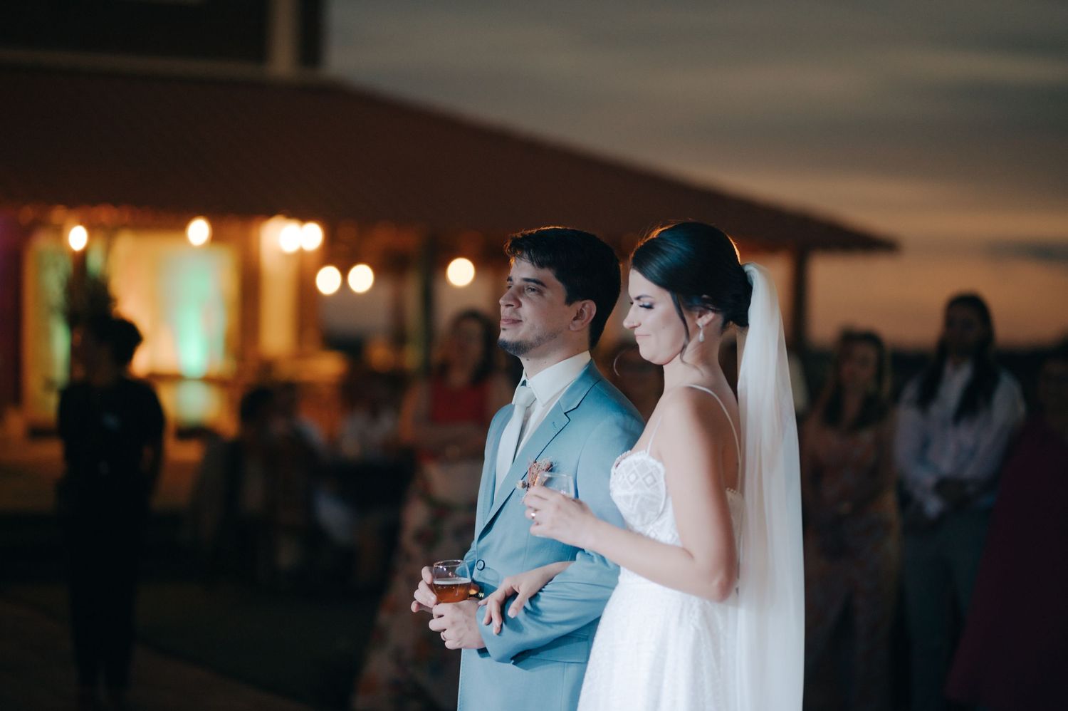 Evening wedding reception with couple standing together under warm lighting.