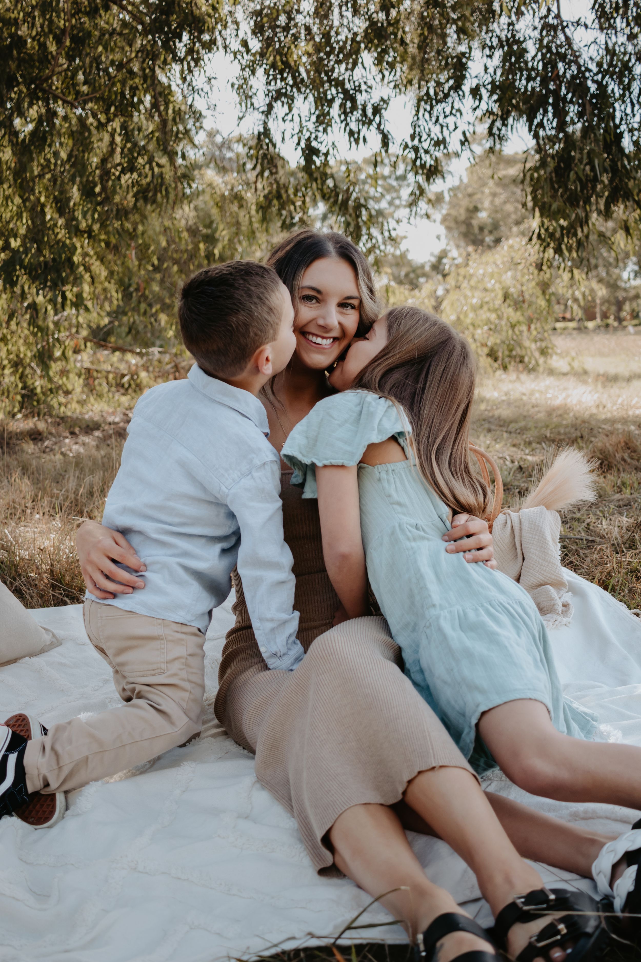 Brother and sister kissing their mum on the cheek.