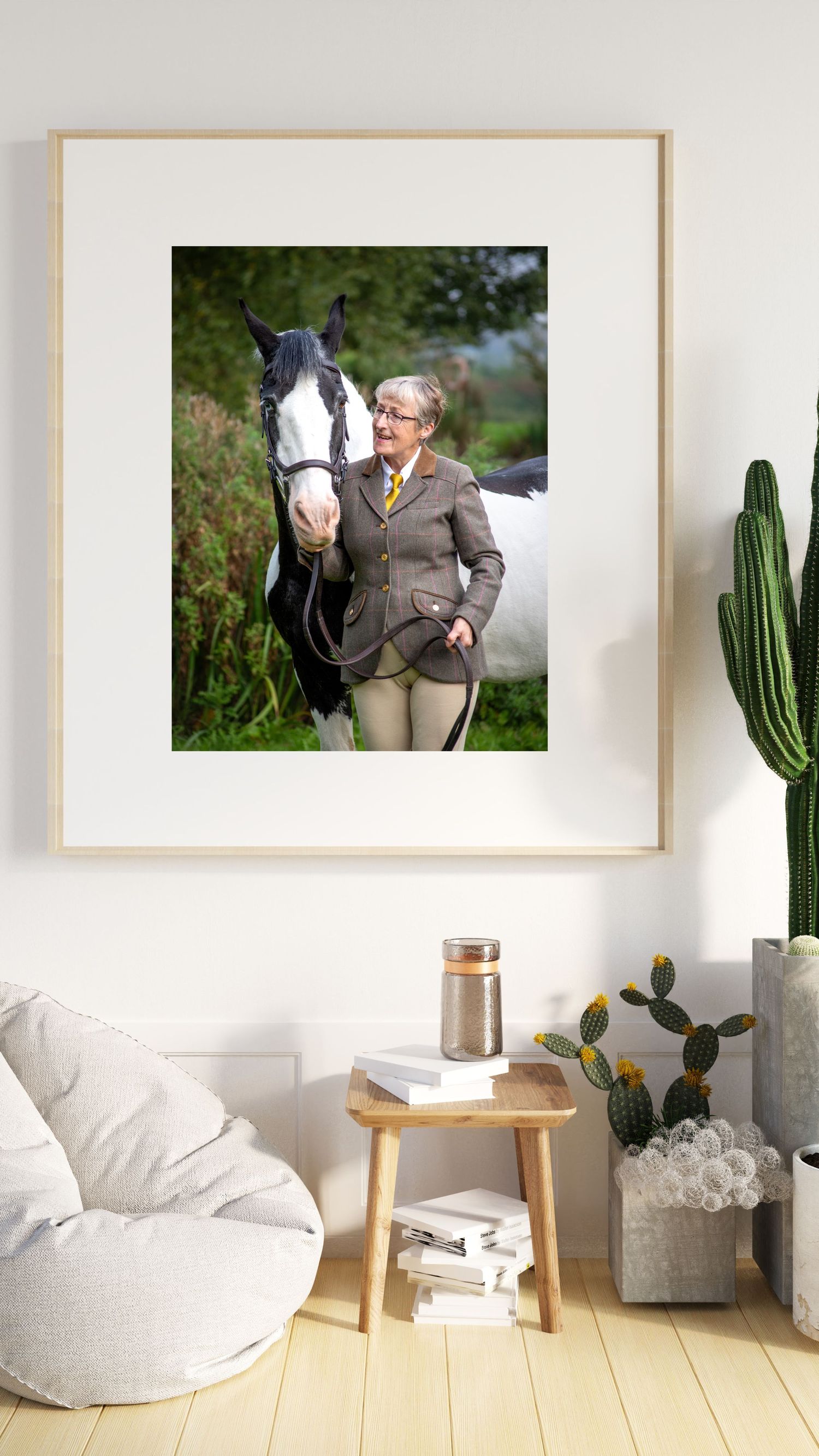 Black and white horse with distinctive markings stands in a garden setting next to decorative cactus.
