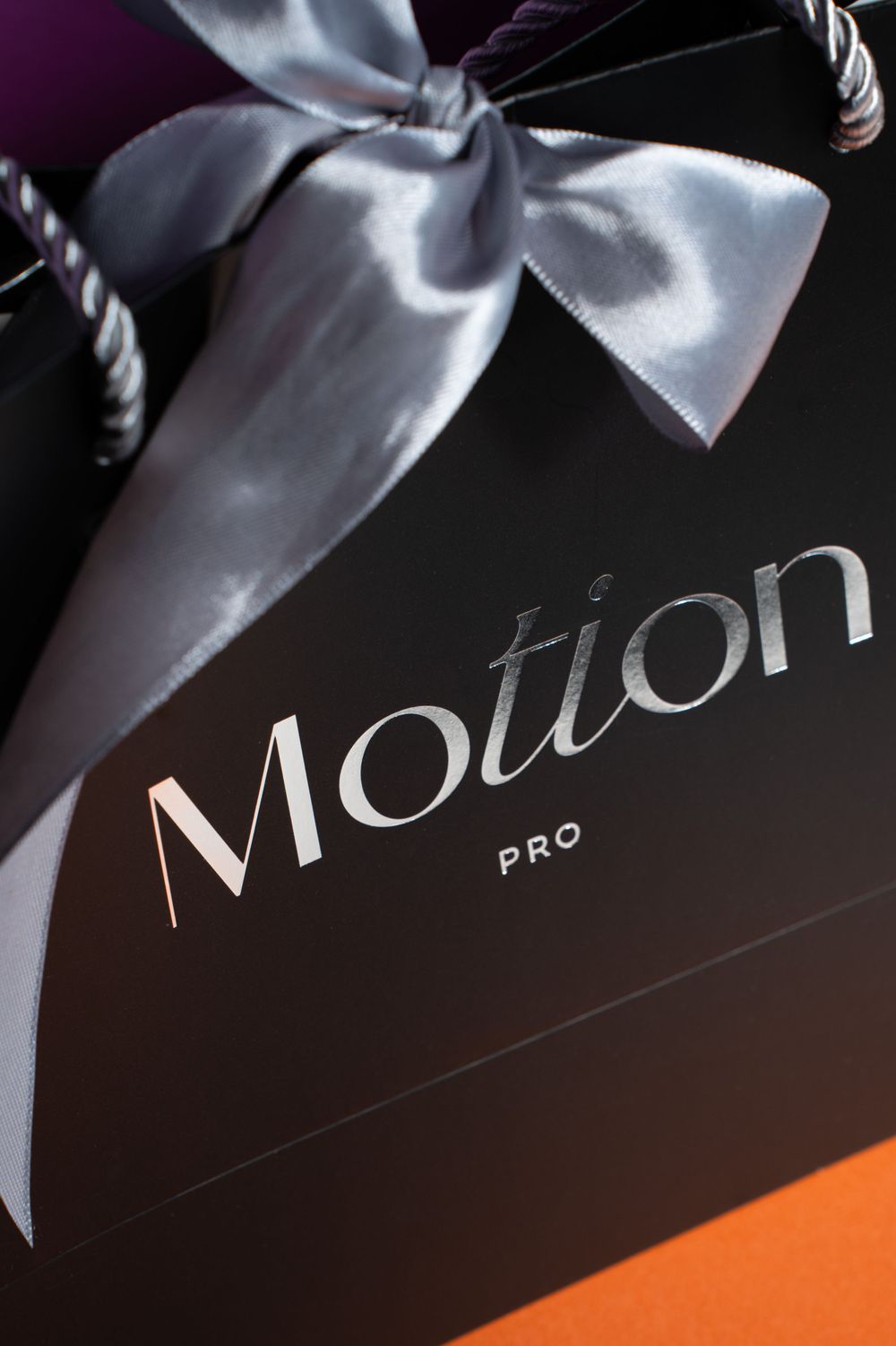 Motion Pro packaging with elegant silver bow against dark background.