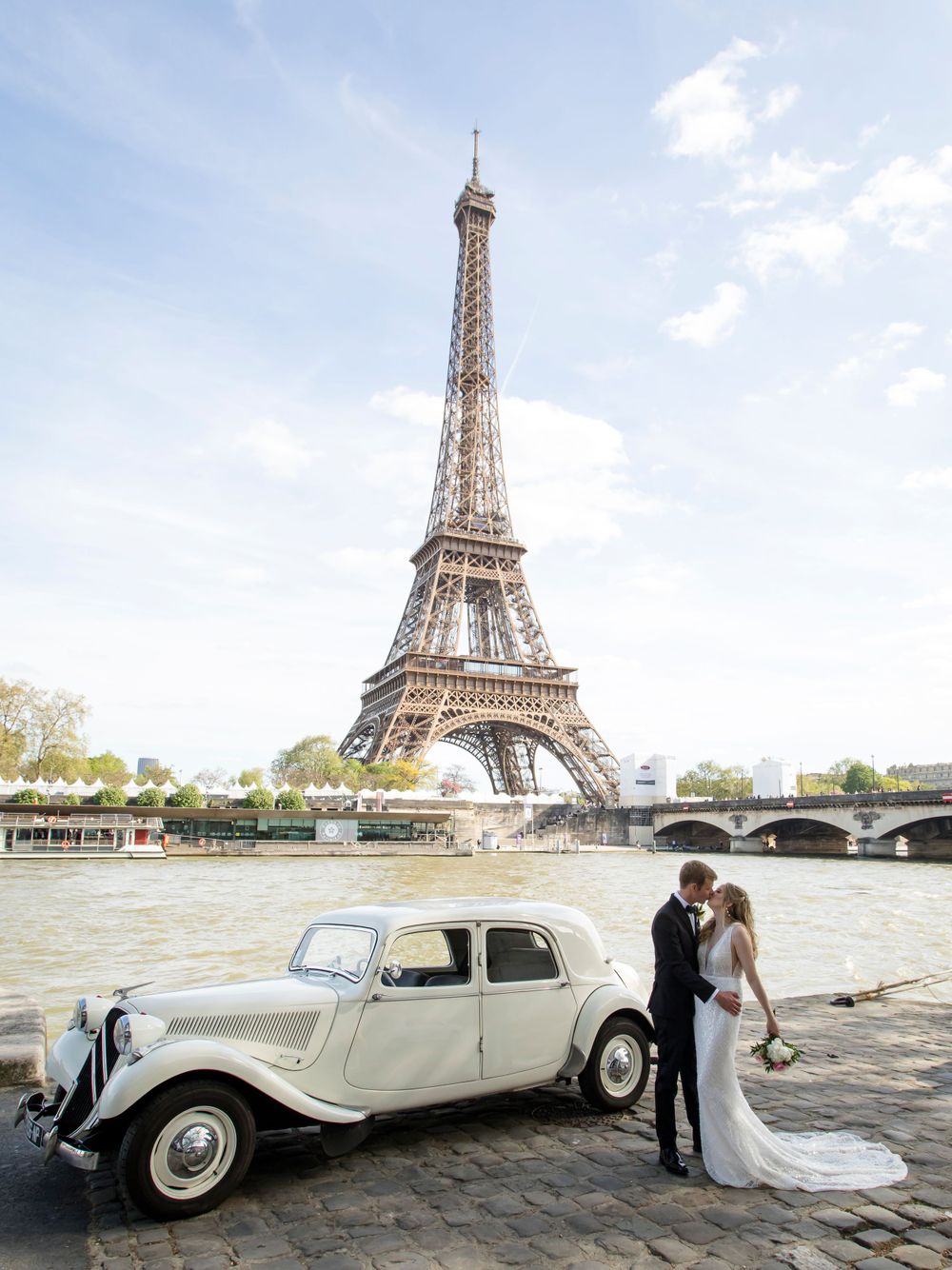 A stunning wedding photo captured by Julien LB by the Eiffel tower with couple standing in front of the vintage white Rolls Royce, Paris