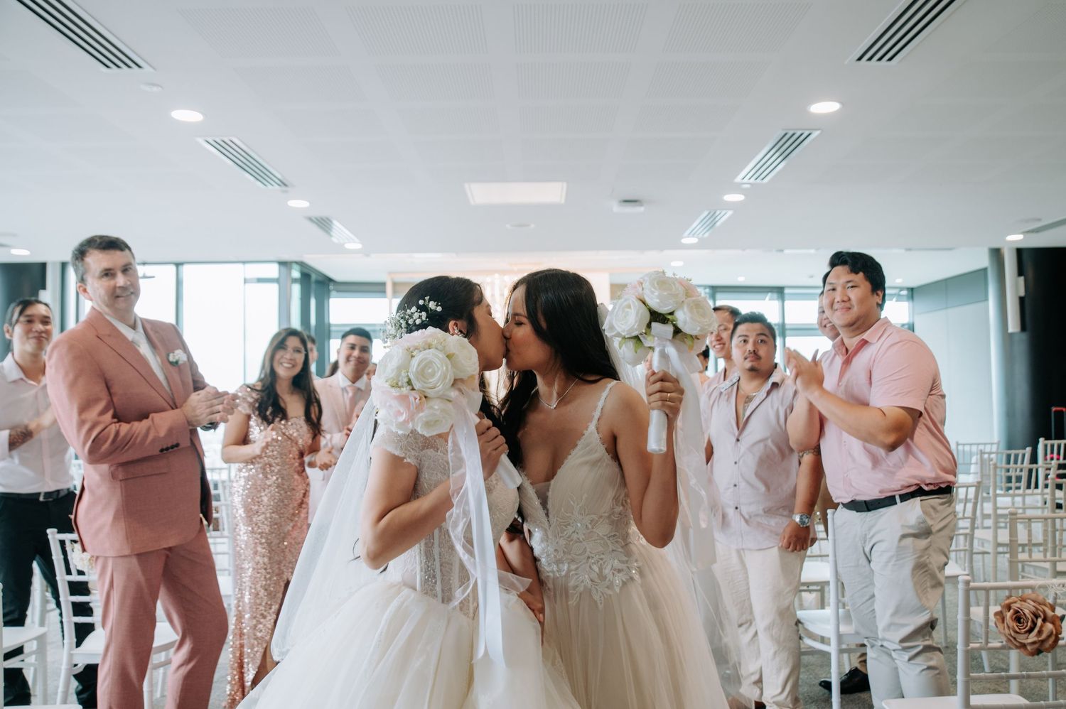 Wedding celebration in a bright room with guests in pastel attire.